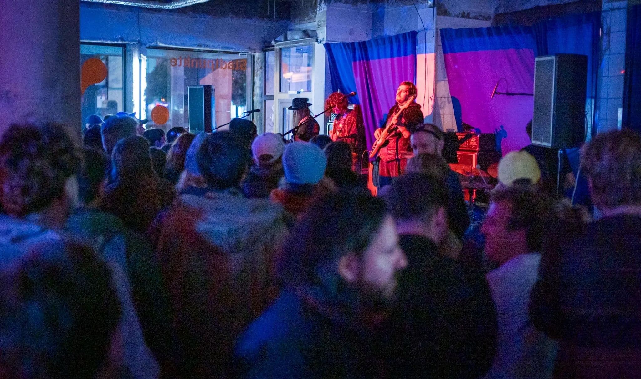 Eine Band spielt in einem dunklen Raum vor zahlreichen Zuschauern