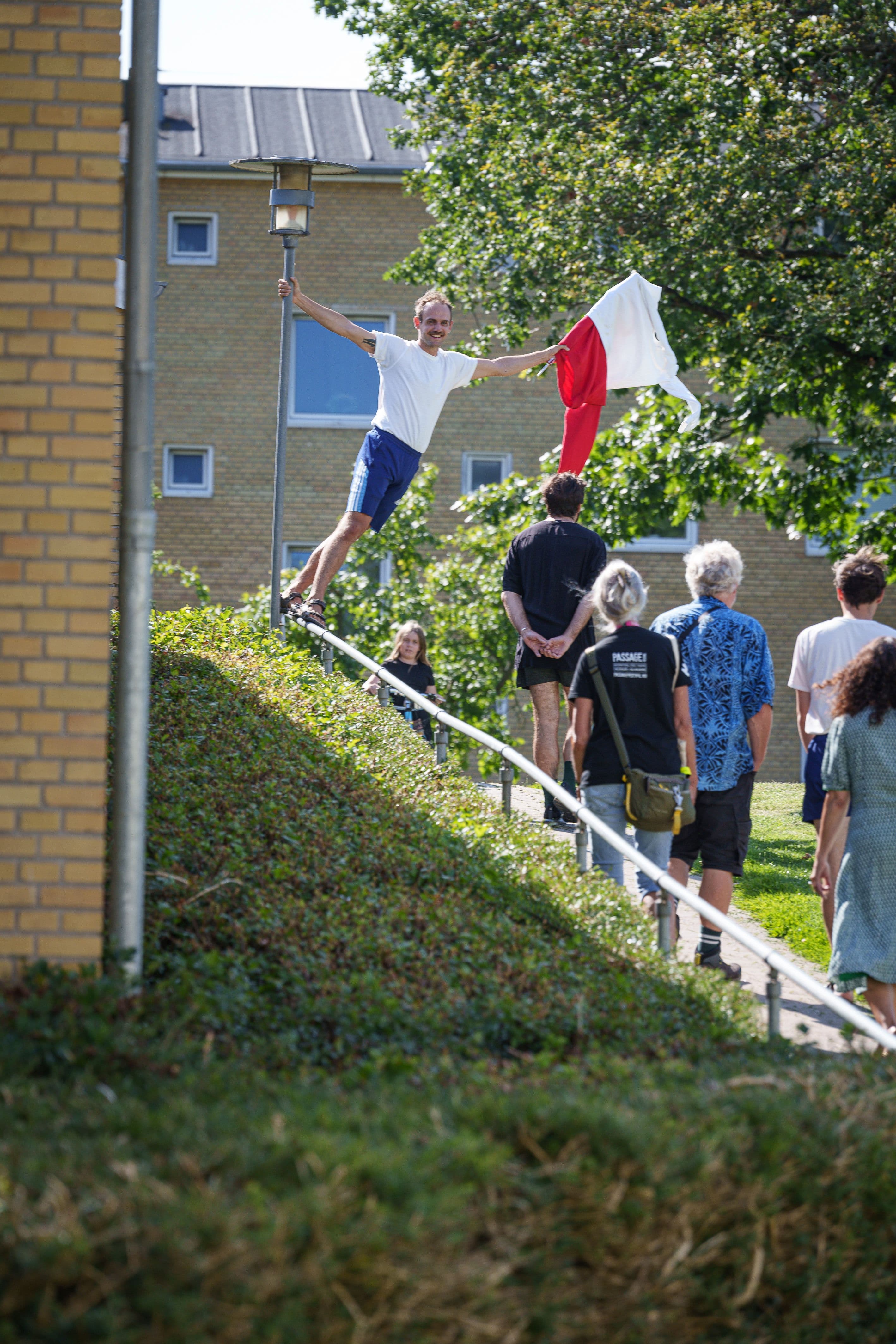 Ein Performaner hält eine weiß/rote Flagge in der Hand und führt eine Gruppe durch das Viertel