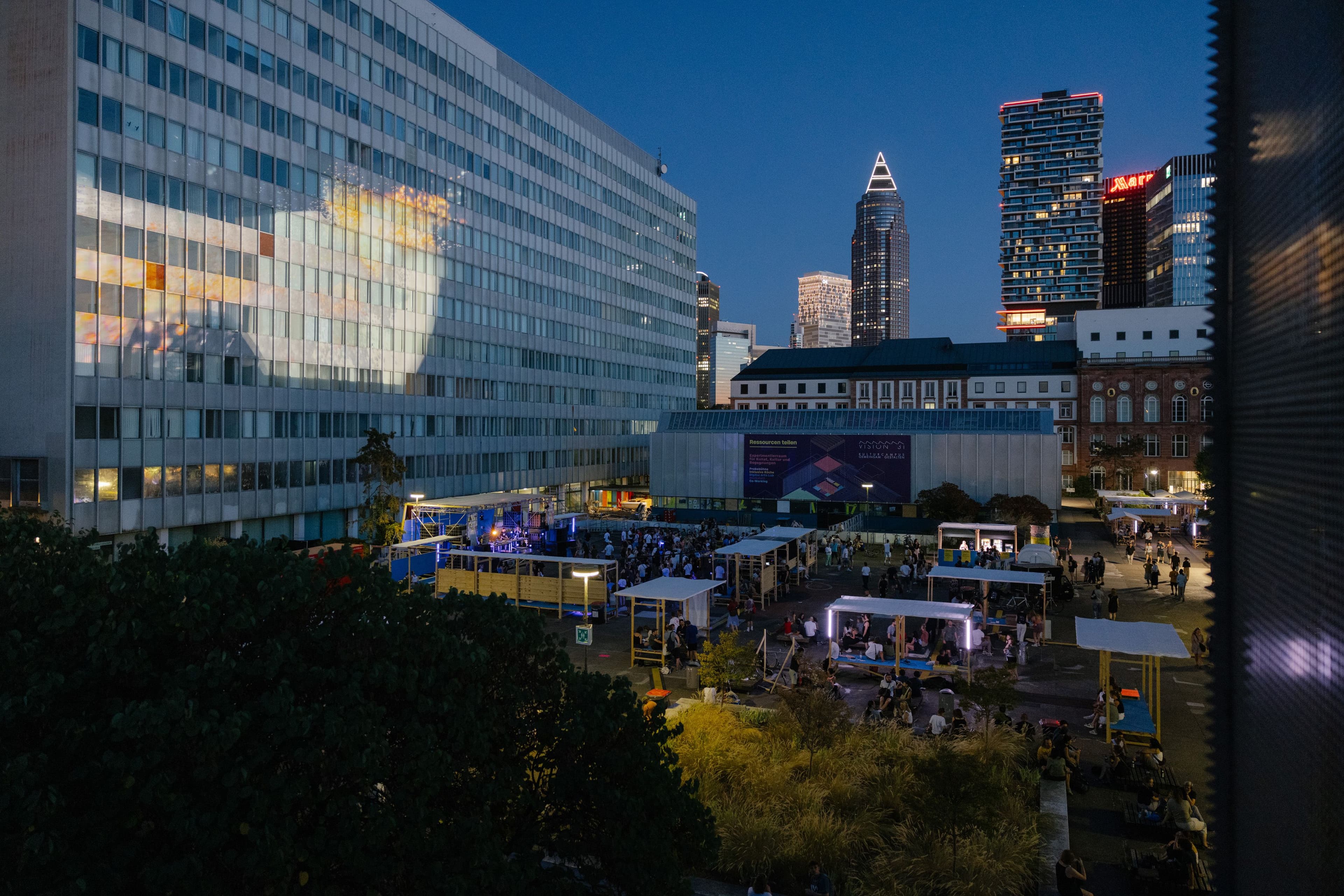 Der Kulturcampus mit Skyline im Hintergrund, voller Menschen und mit Projektion auf dem Juridicum
