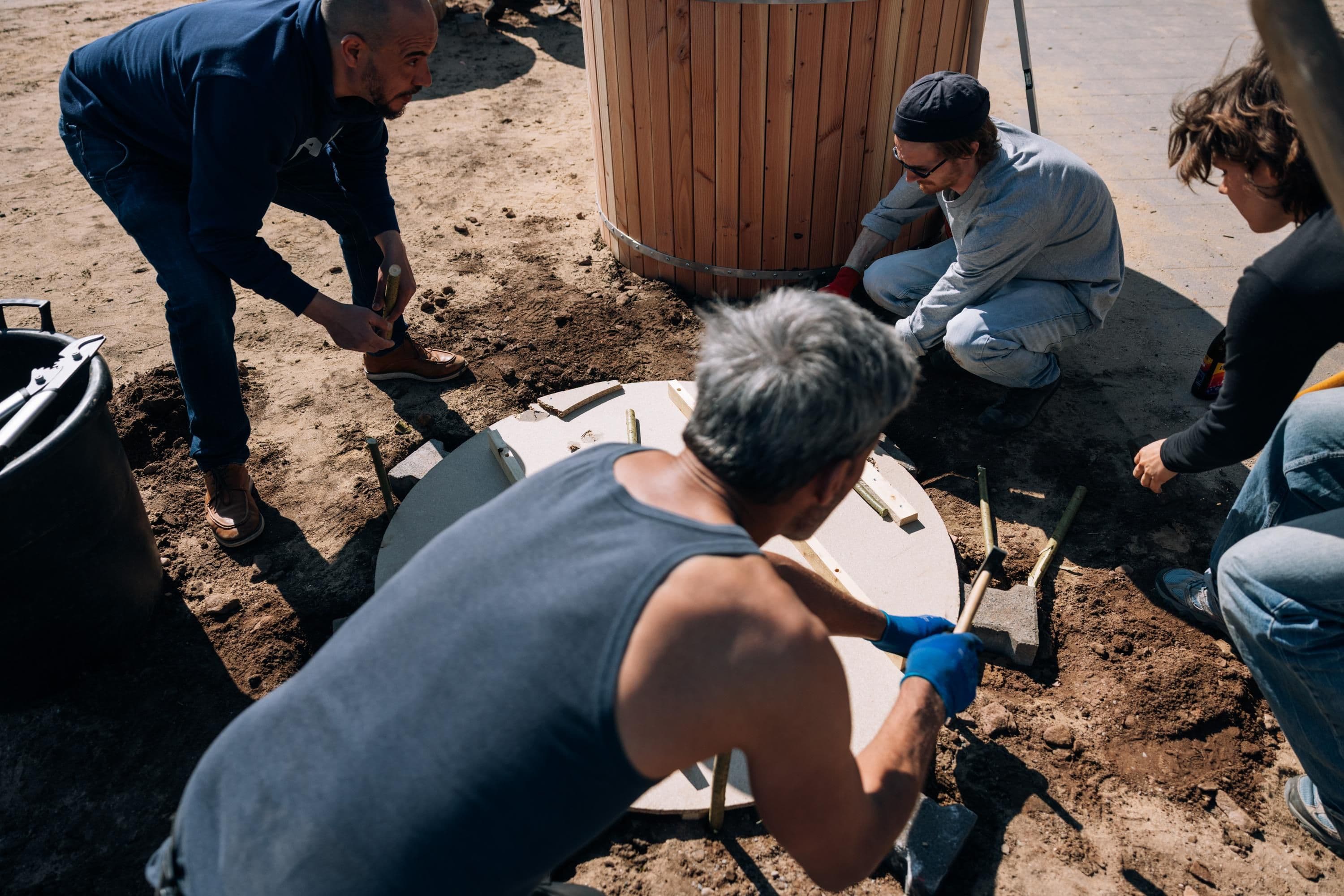 Gemeinsam arbeiten mehrere Menschen an einem Fundament für ein Hochbeet