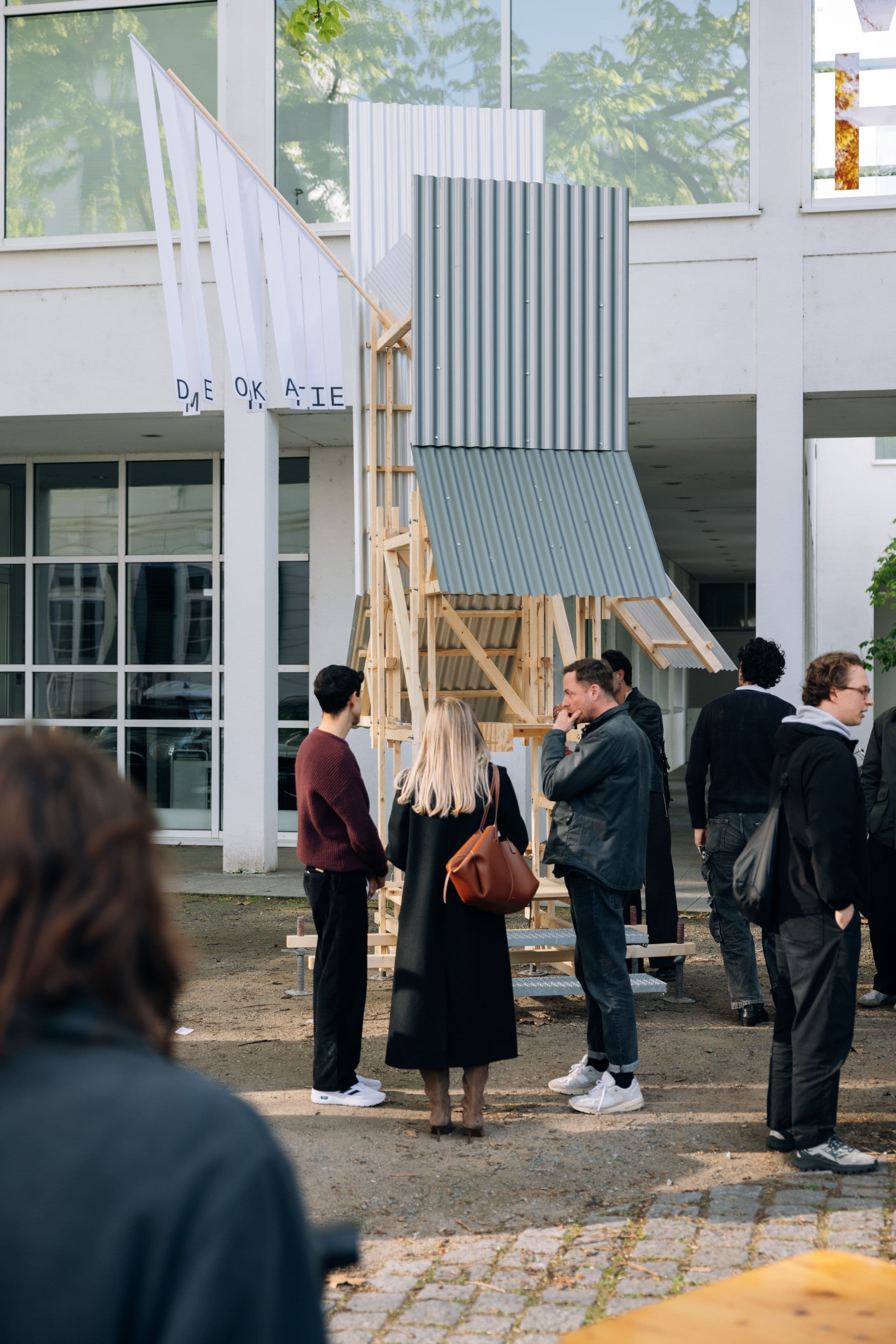 Mehrere Personen stehen vor einer Wahlkabine aus Holz und Blech.