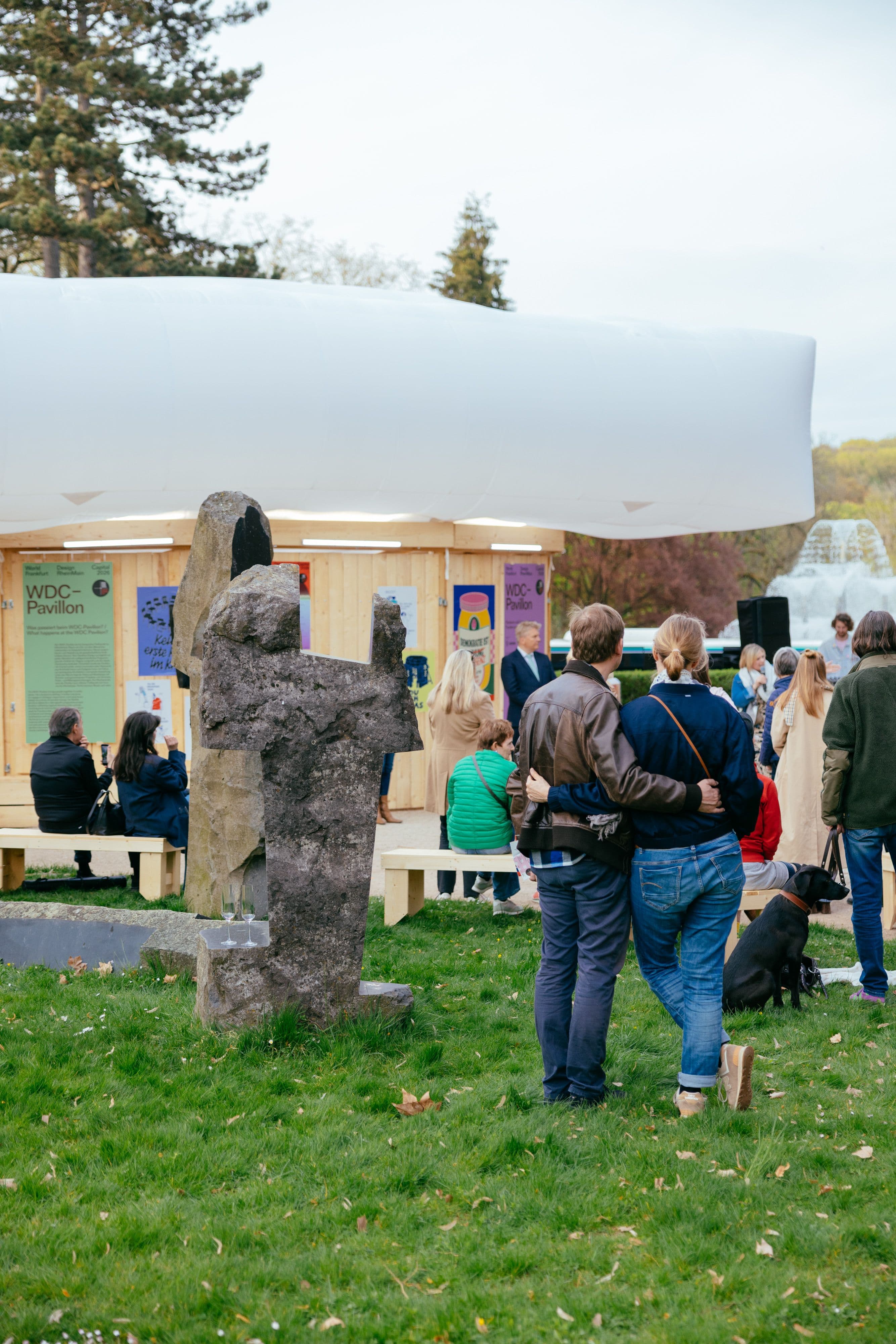 Menschen vor dem Pavillon stehen auf der Wiese