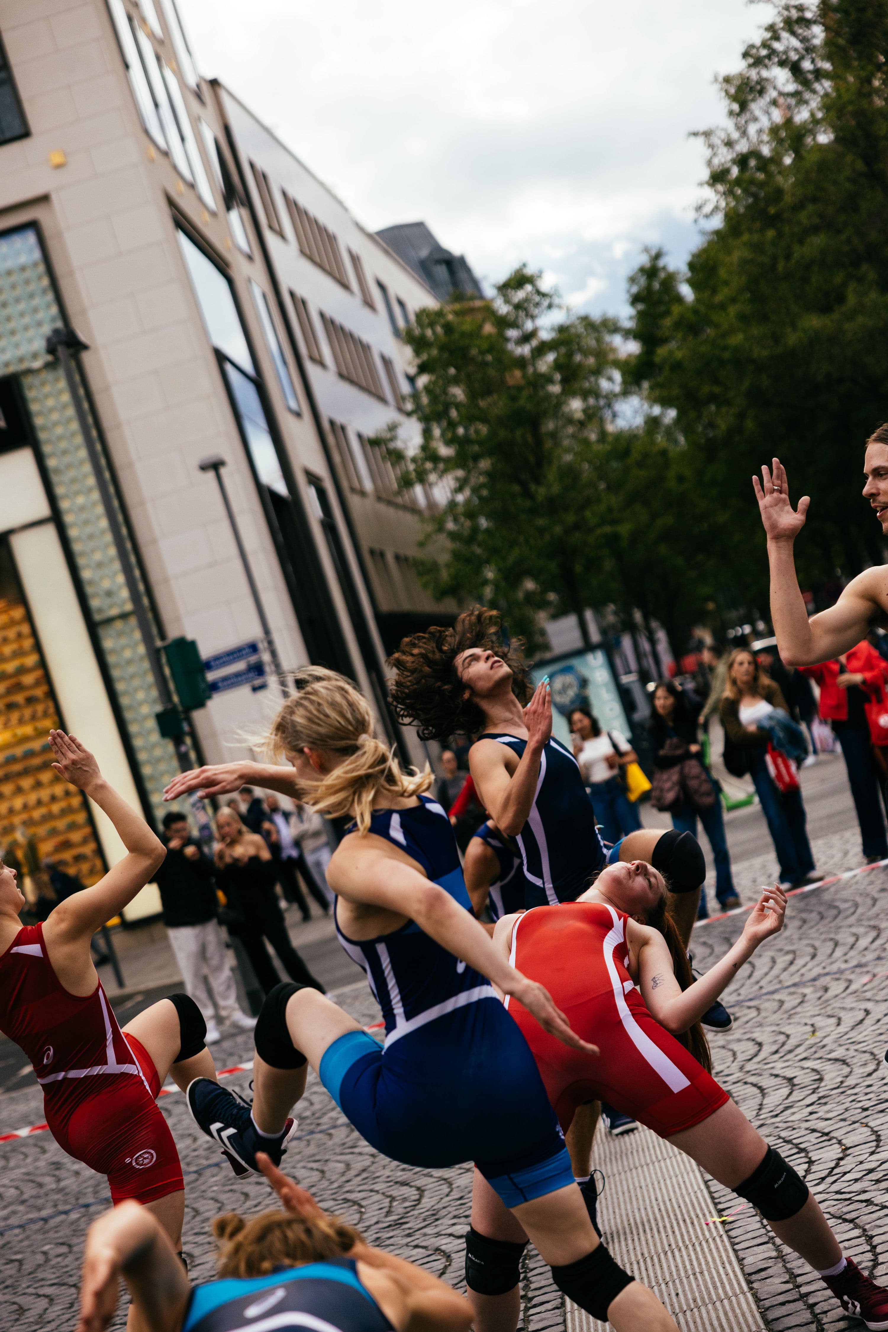 Personen mit roten und blauen Sportanzügen tanzen mitten in Frankfurt.