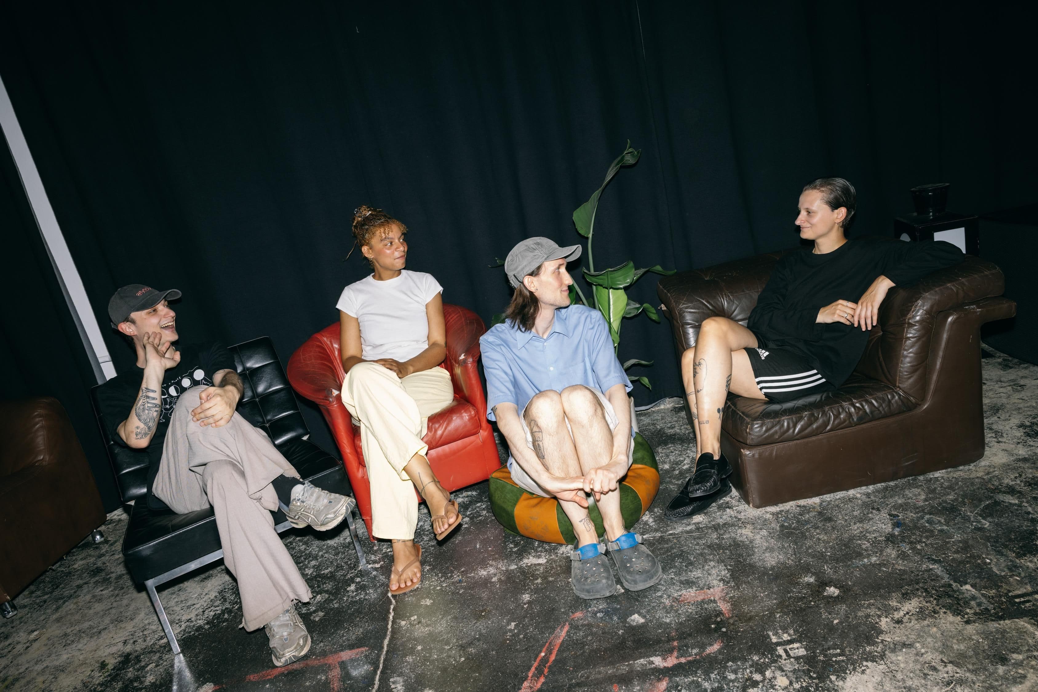4 Personen sitzen auf Sofas beieinander.