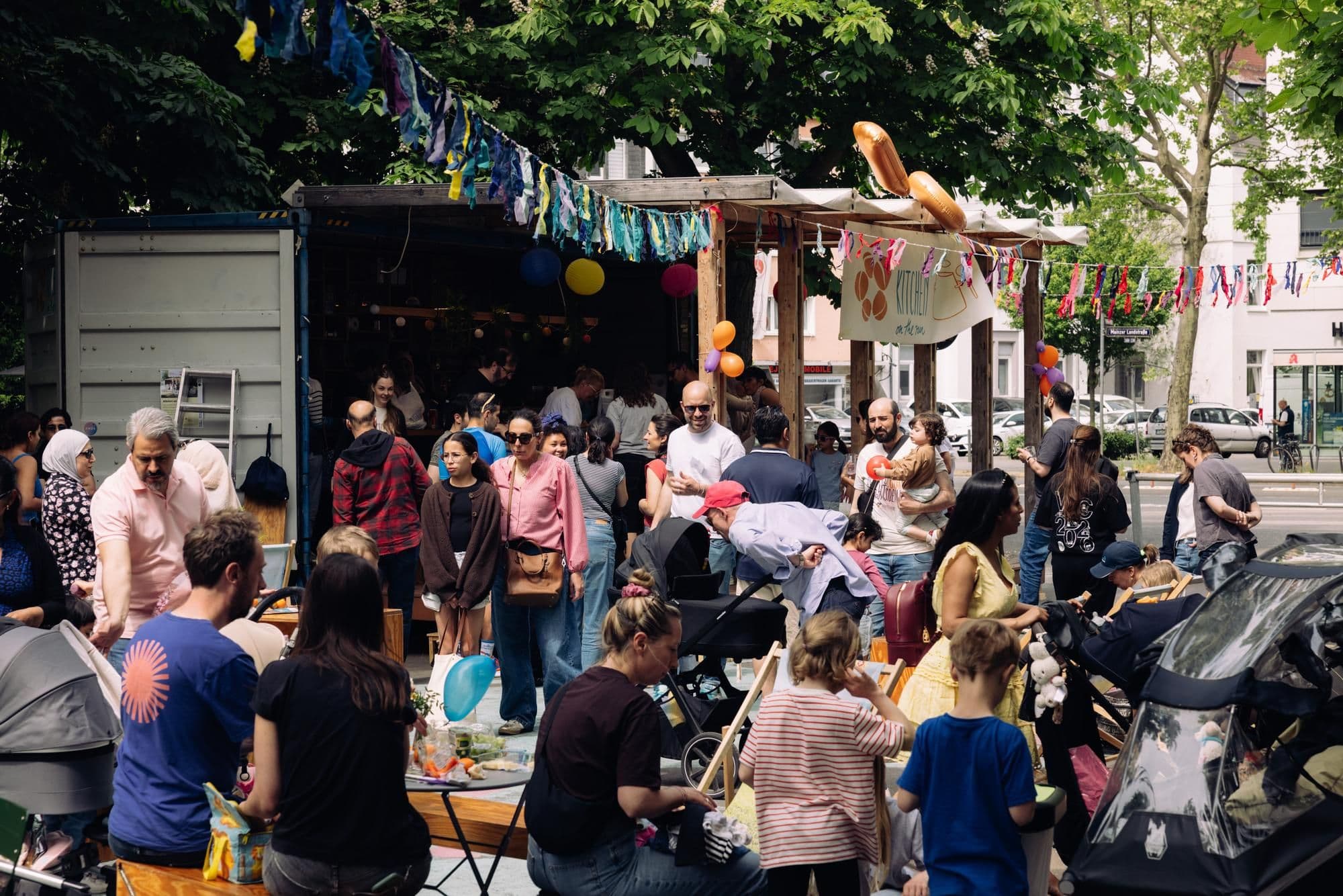 Viele Personen stehen und sitzen bei gutem Wetter bei einem Picknick