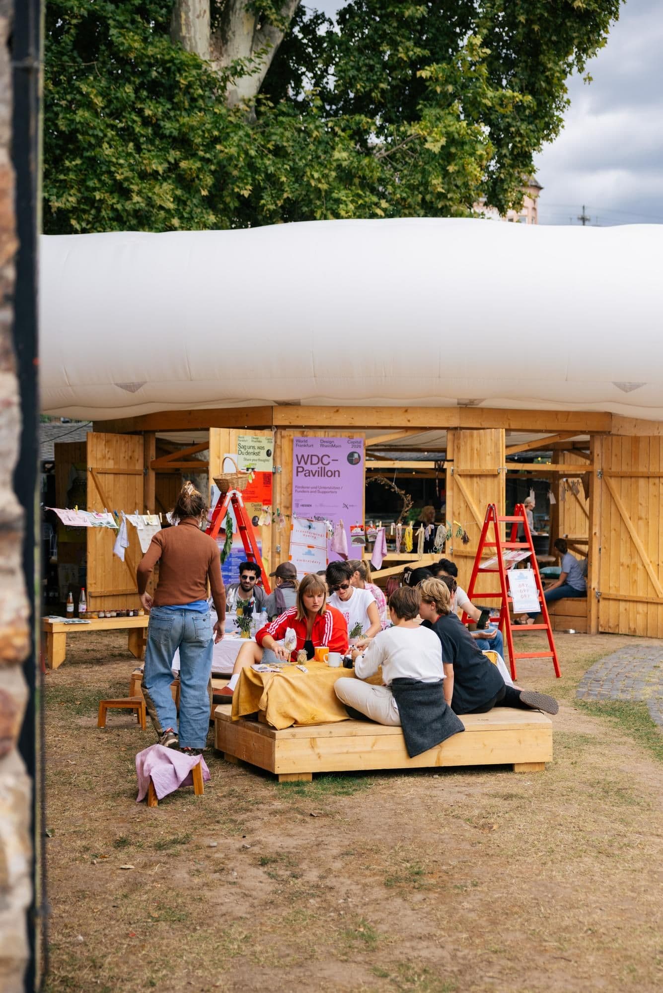 Menschen sitzen zusammen im Grünen am Pavillon.