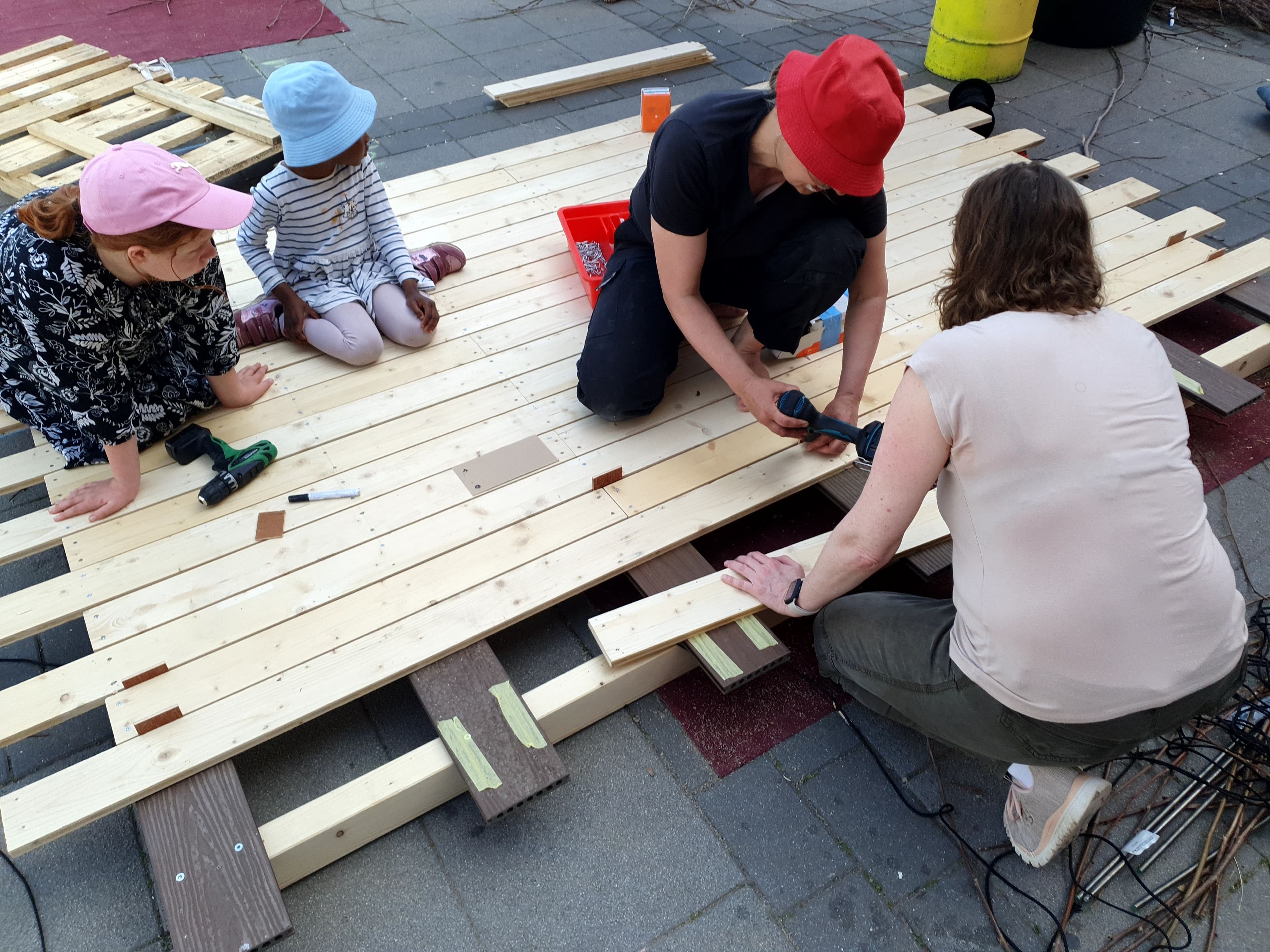 Menschen arbeiten auf dem Frankfurter Atzelbergplatz mit Holz. 