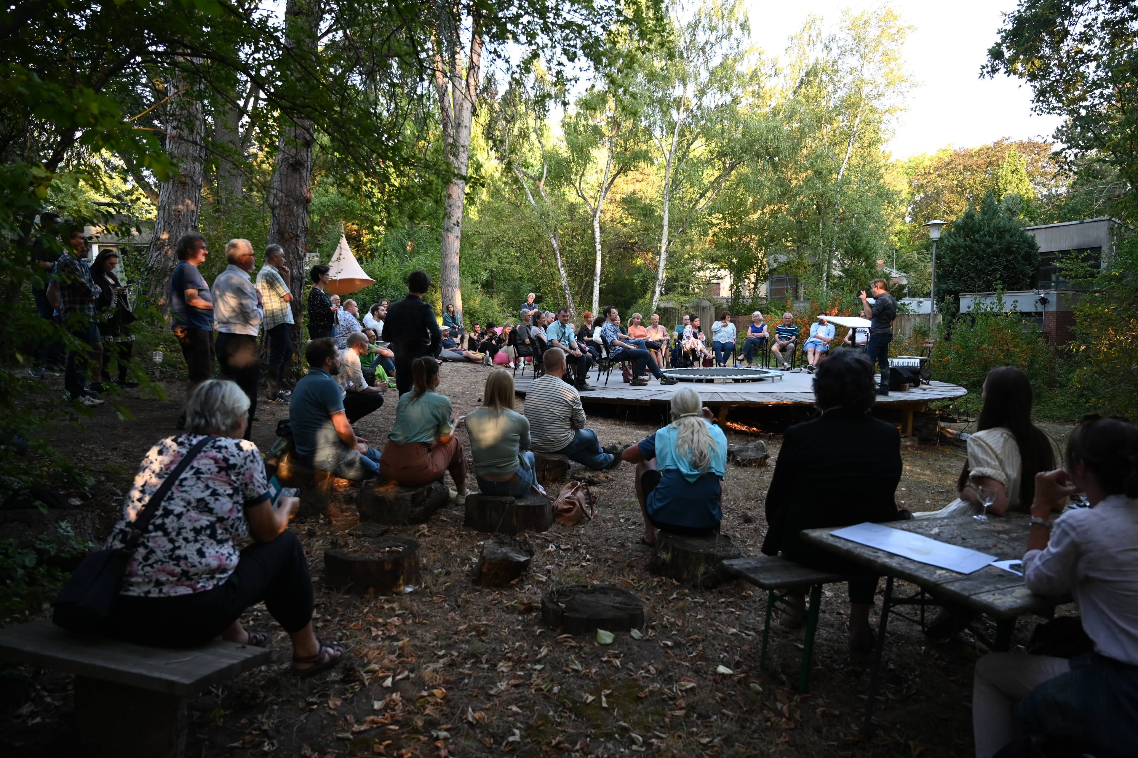 Menschen hören auf einer Waldbühne einer Podiumsdiskussion zu