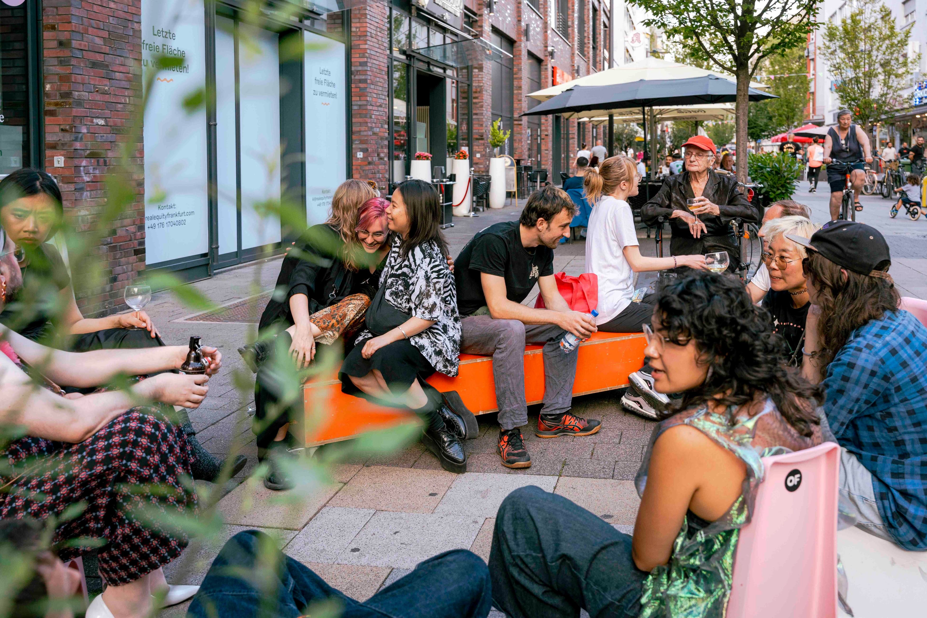 Menschen sitzen auf bunten Bänken vor dem Scape Offenbach