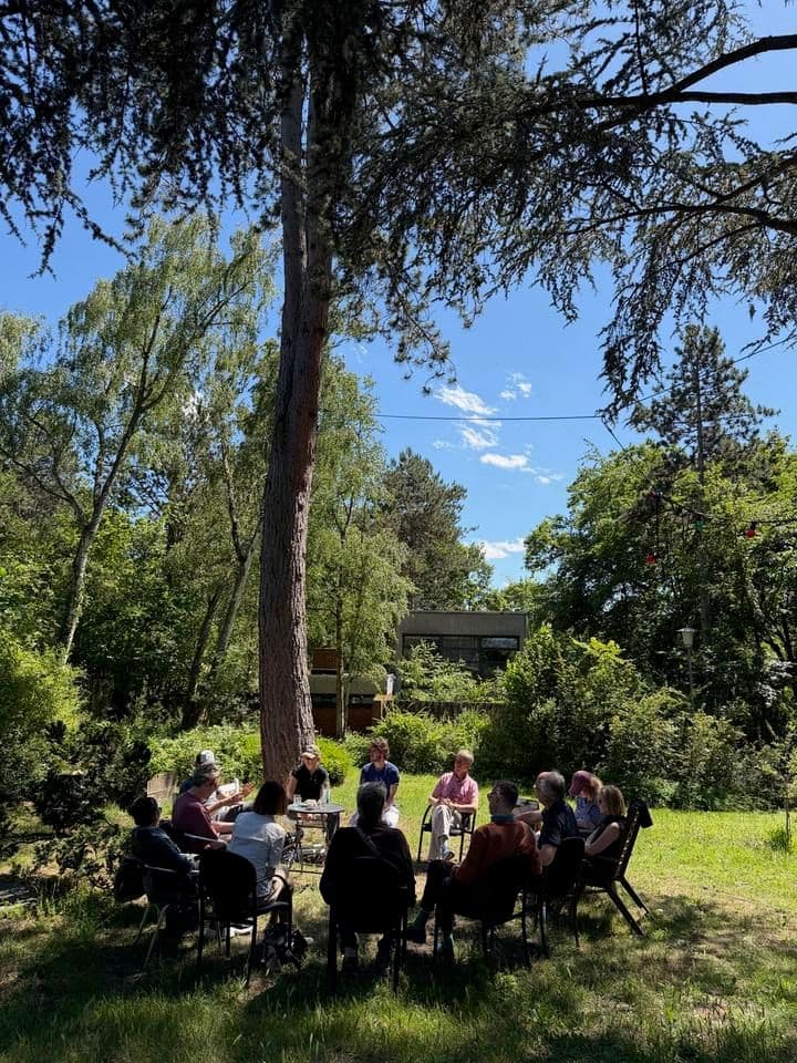 Menschen sitzten im Stuhlkreis im Grünen