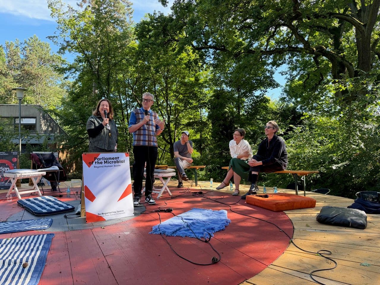 Menschen hören auf einer Waldbühne einer Podiumsdiskussion zu