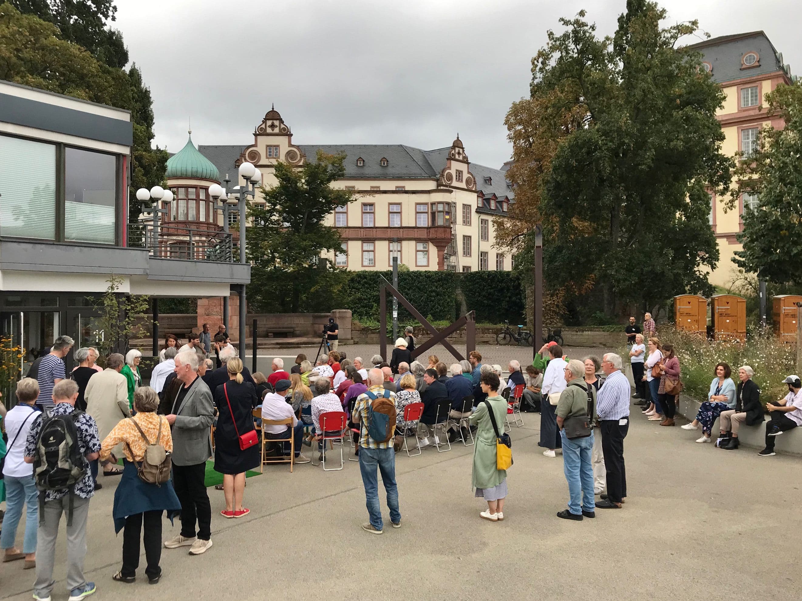 Menschen stehen im Rahmen einer Vernissage auf einem Platz in Darmstadt