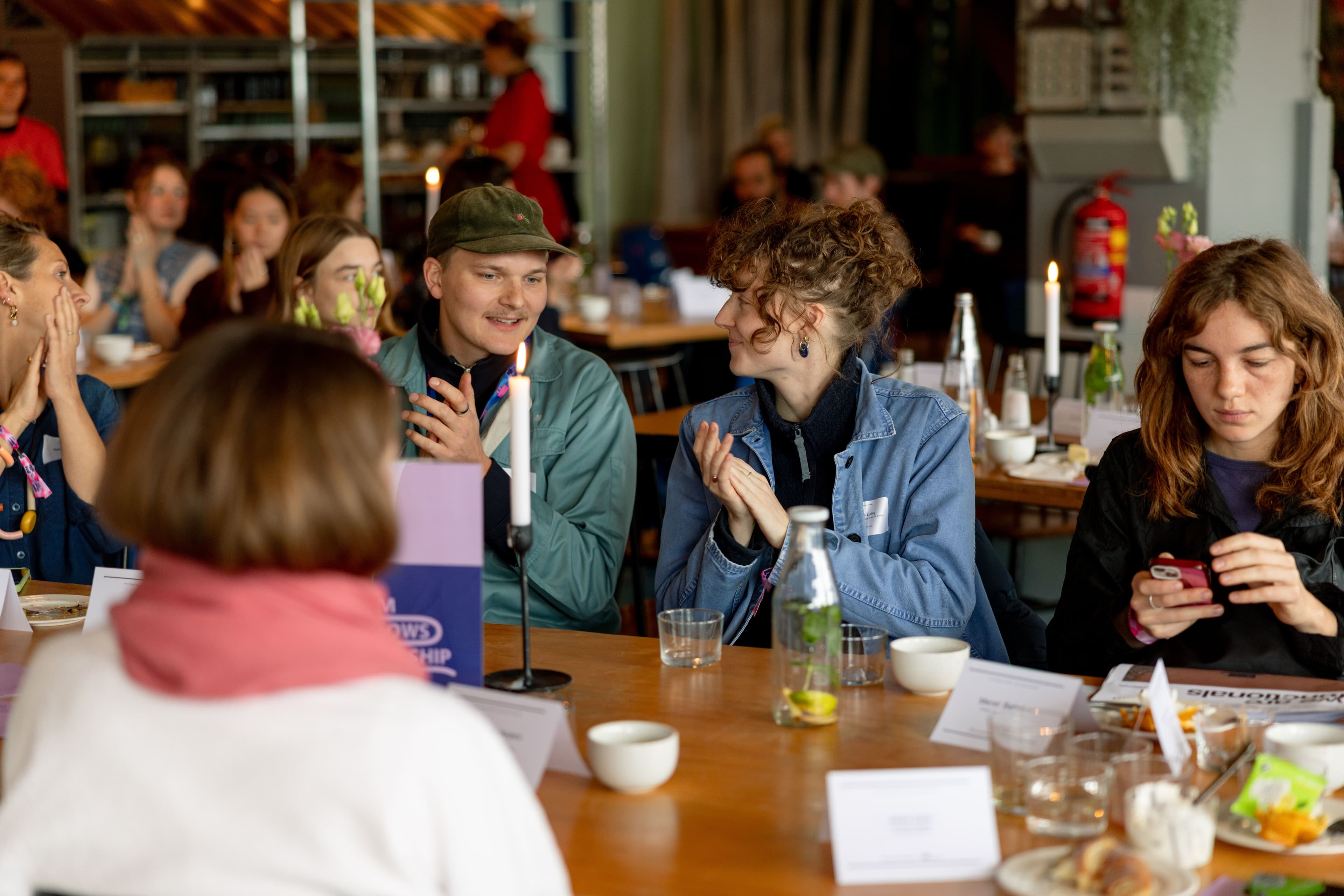 Junge Menschen sitzen gemeinsam an einem großen Tisch und unterhalten sich angeregt