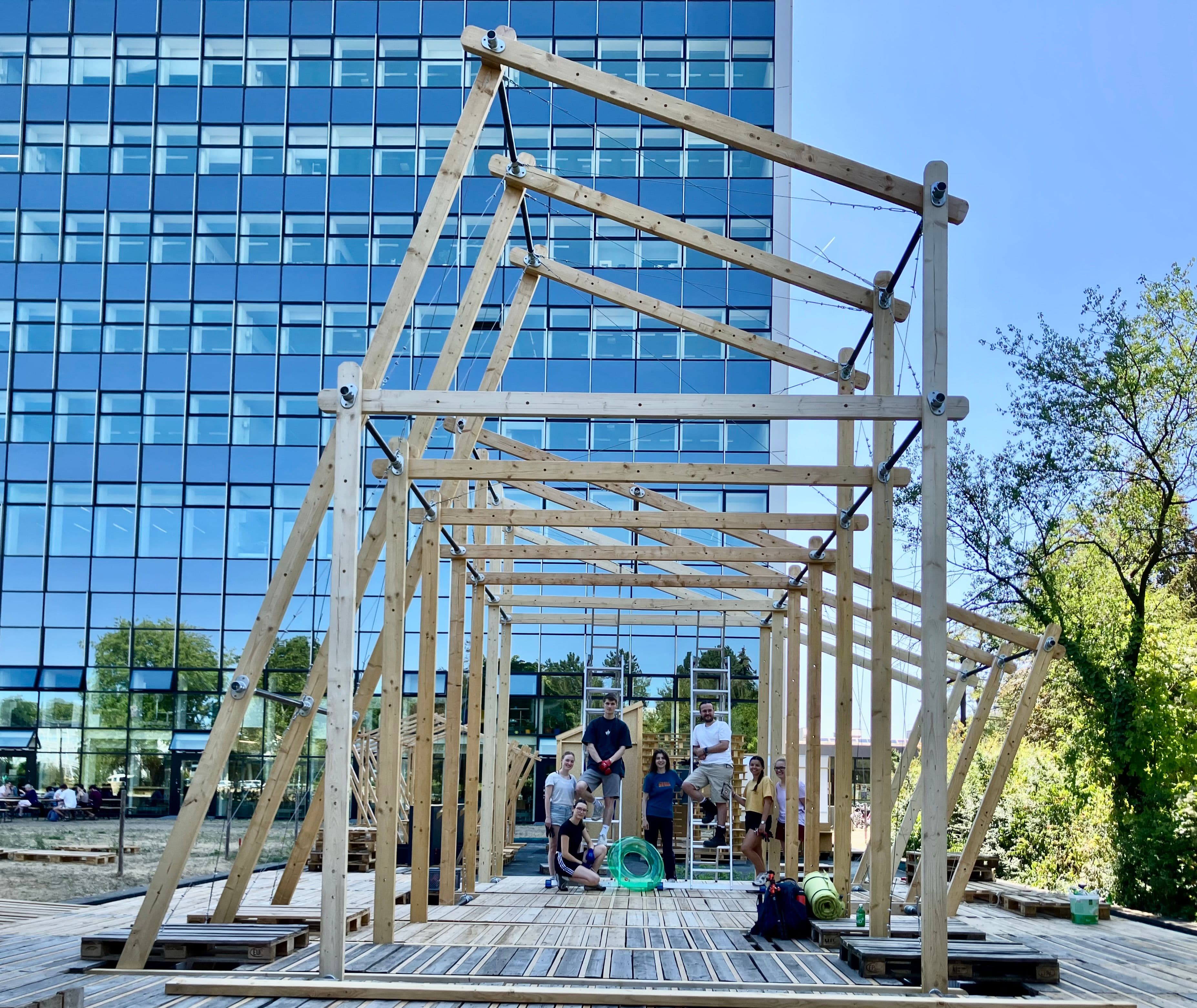 Eine Holzkonstruktion steht auf einem Platz vor einem Hochhaus