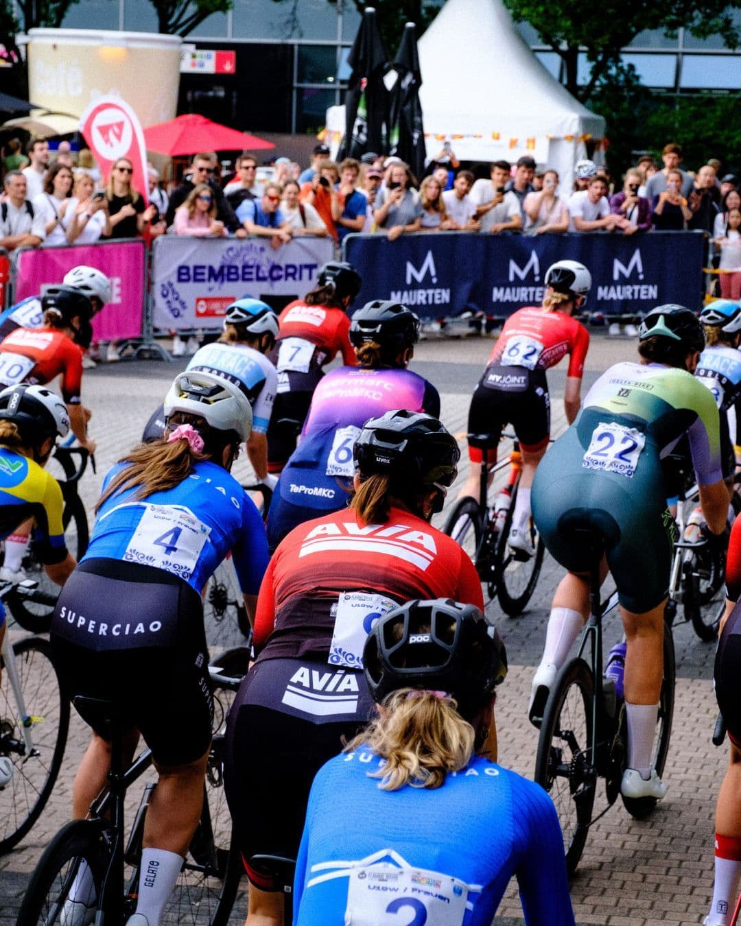 Ein Radrennen findet auf der Straße statt, das von Menschen am Straßenrand beobachtet wird.