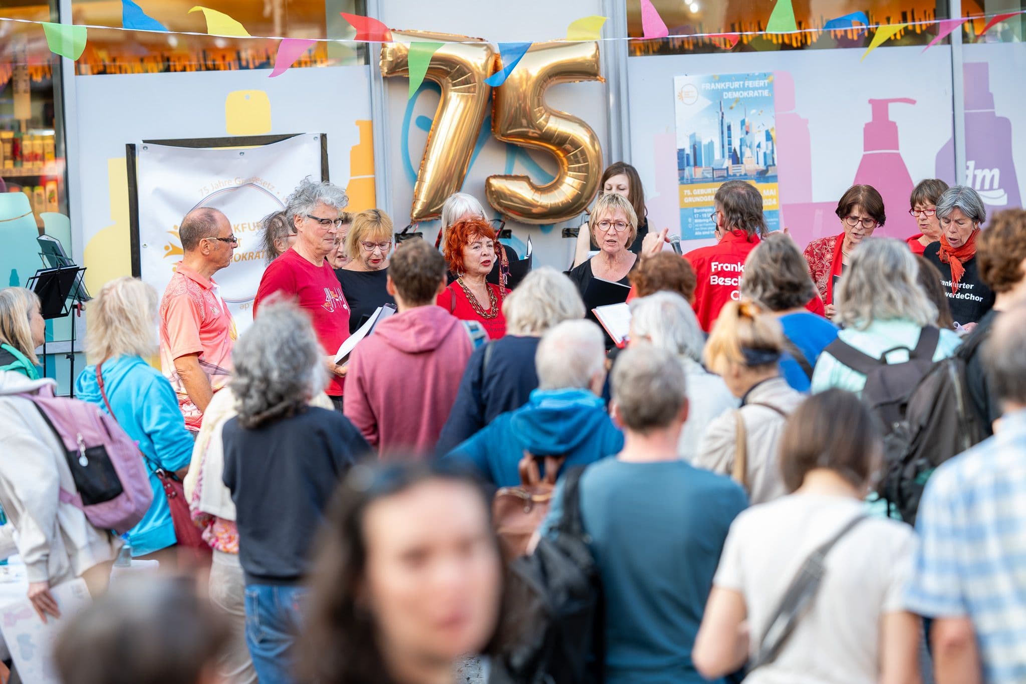 Eine Menschenmenge schaut einer Gruppe von Leuten zu, die vor einem Geschäft singt.