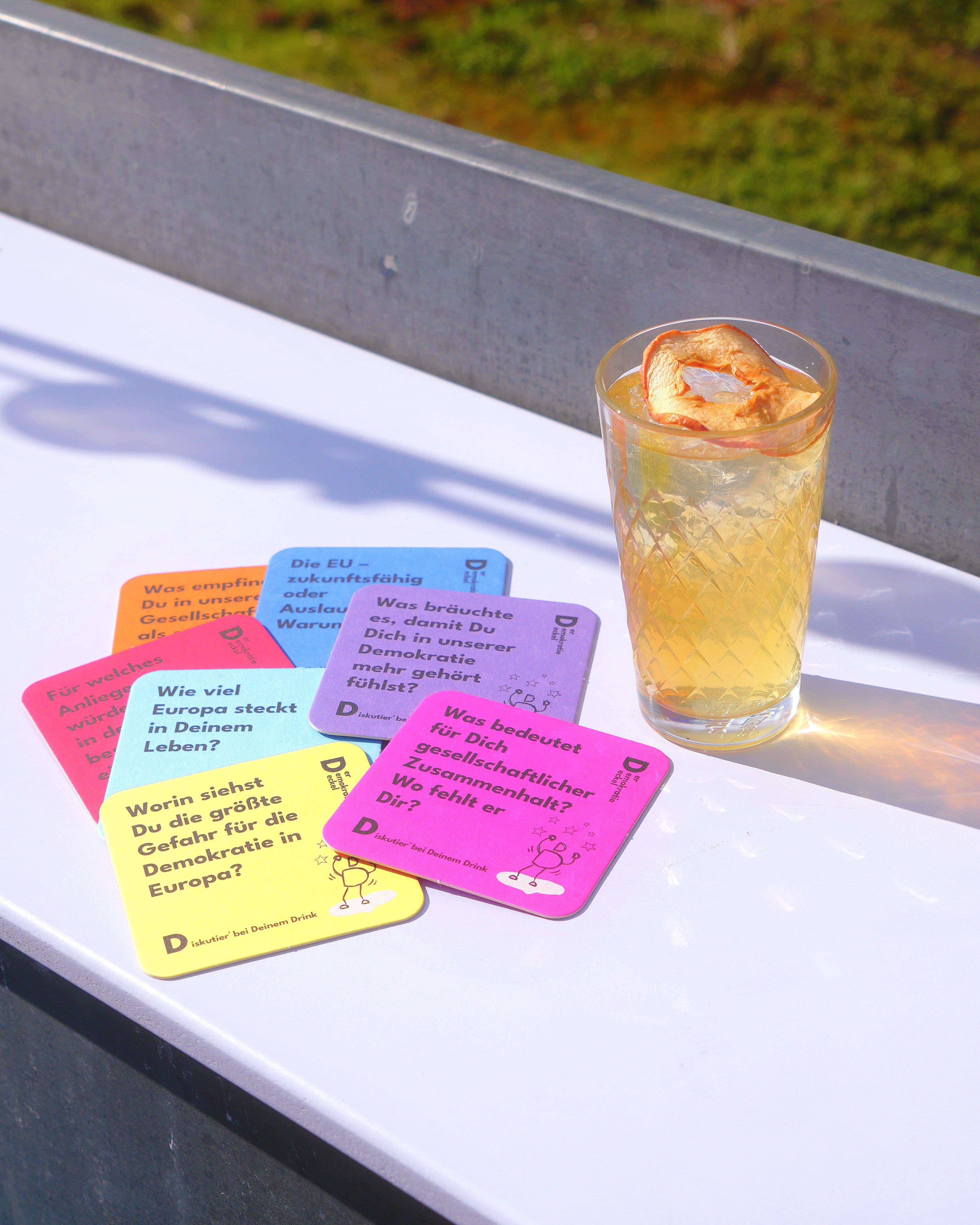 Viele Bierdeckel mit Fragen drauf und ein volles geripptes Glas