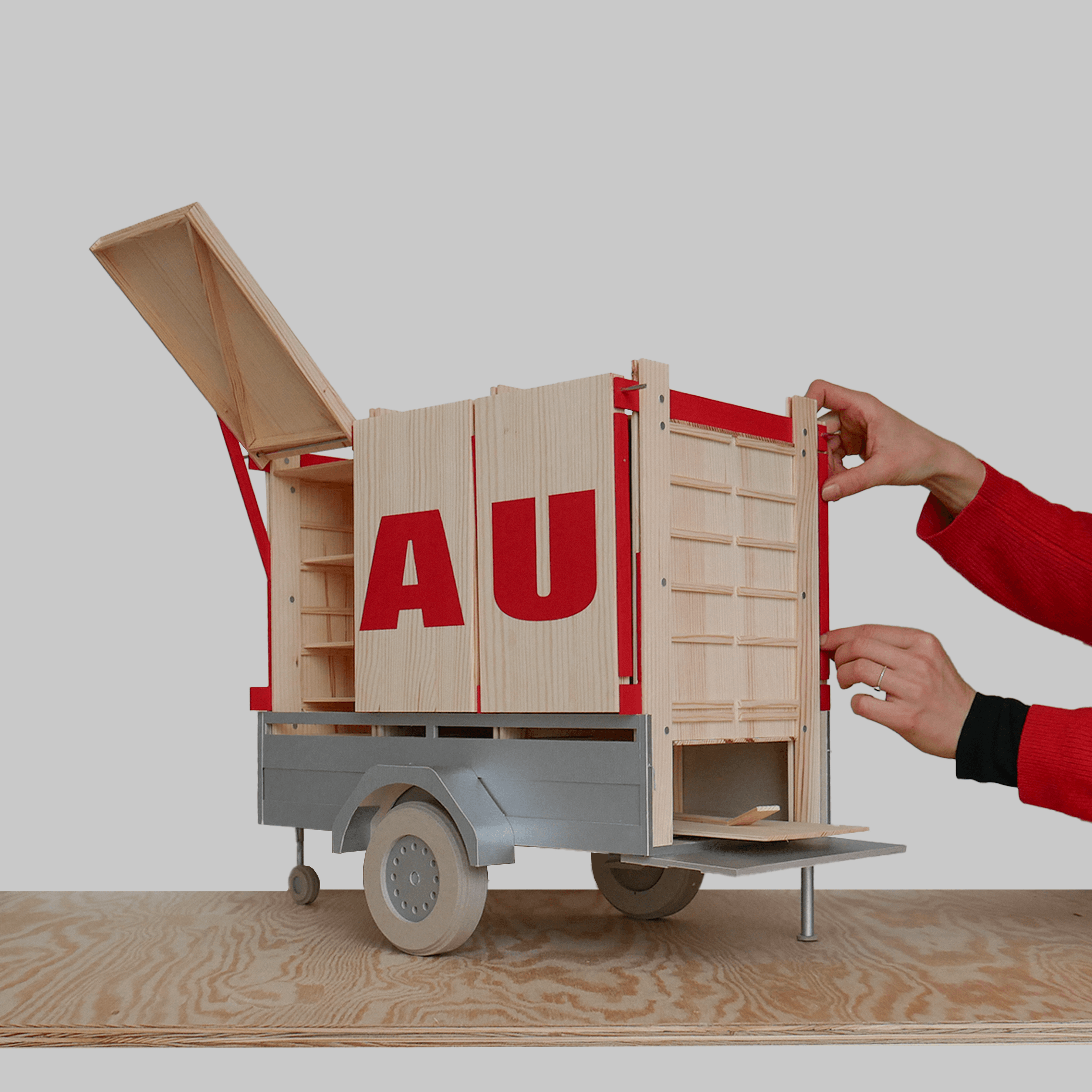 Zwei Hände arbeiten an einem Modell eines modularen Anhängers