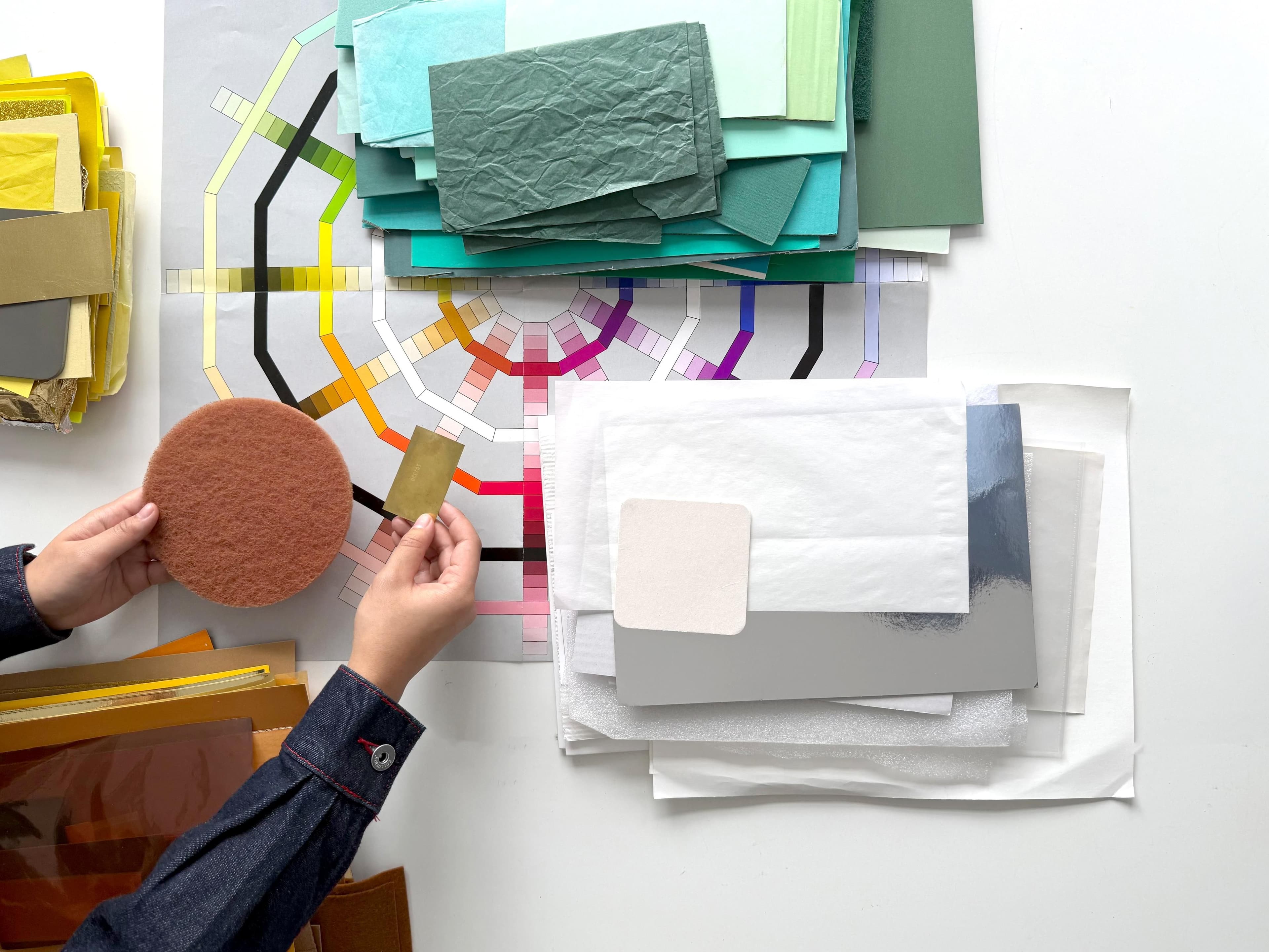 Eine Hand arbeitet mit unterschiedlichen Materialien an einem Tisch