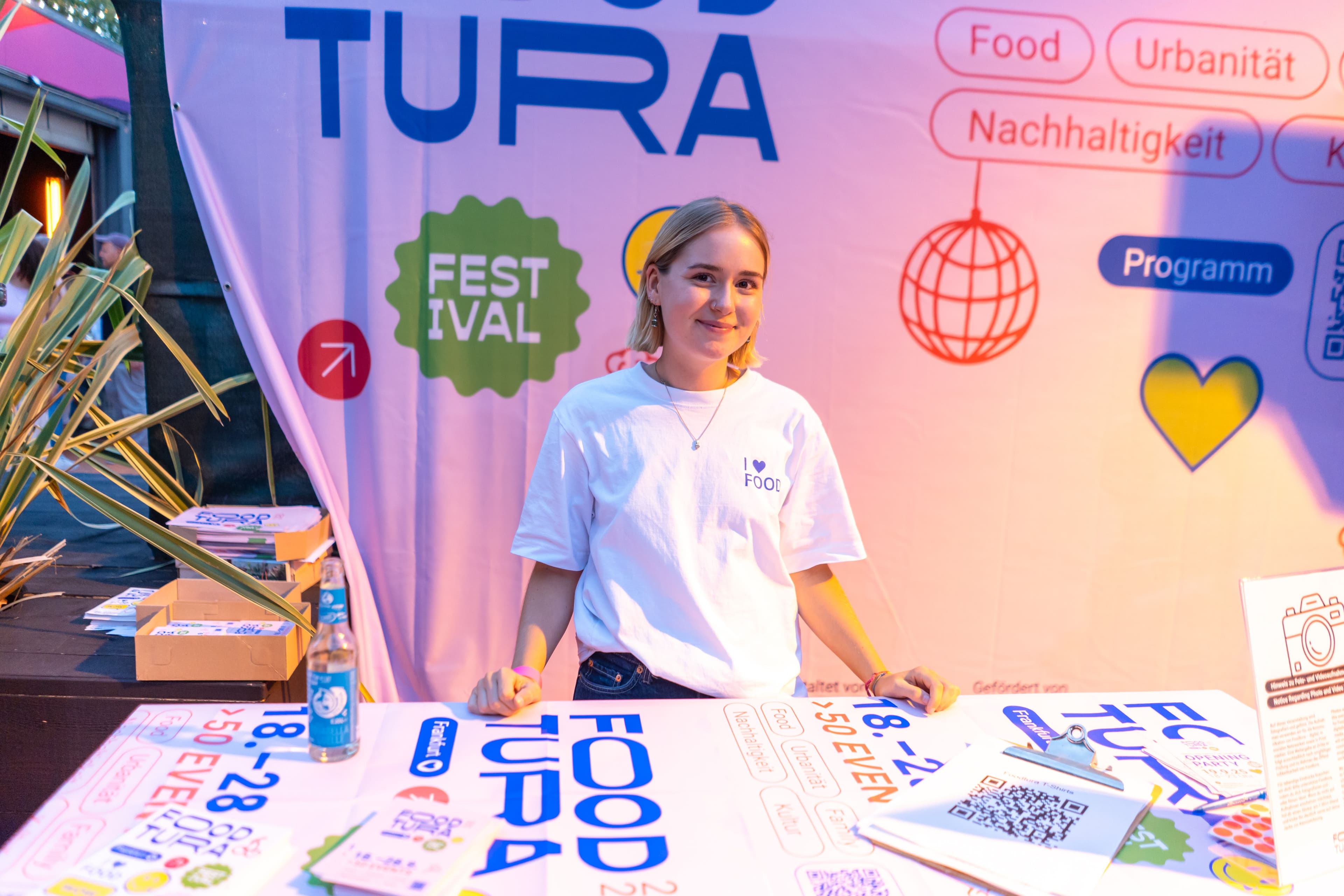 Eine Frau steht an einem Stand von Foodtura und schaut in die Kamera