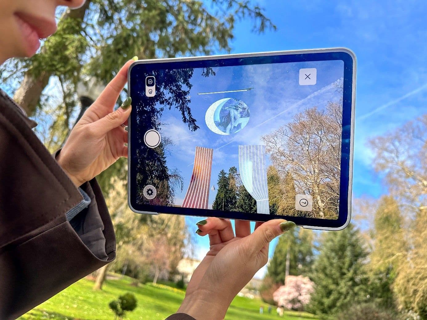Hände halten ein Tablet in den Himmel auf dem etwas mit virtual Reality zu sehen ist