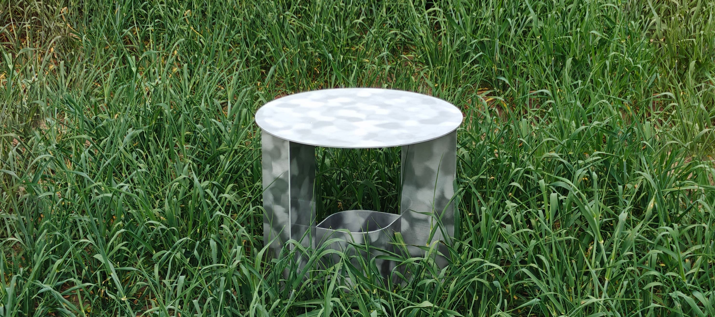 Ein Metallhocker steht in einer Wiese