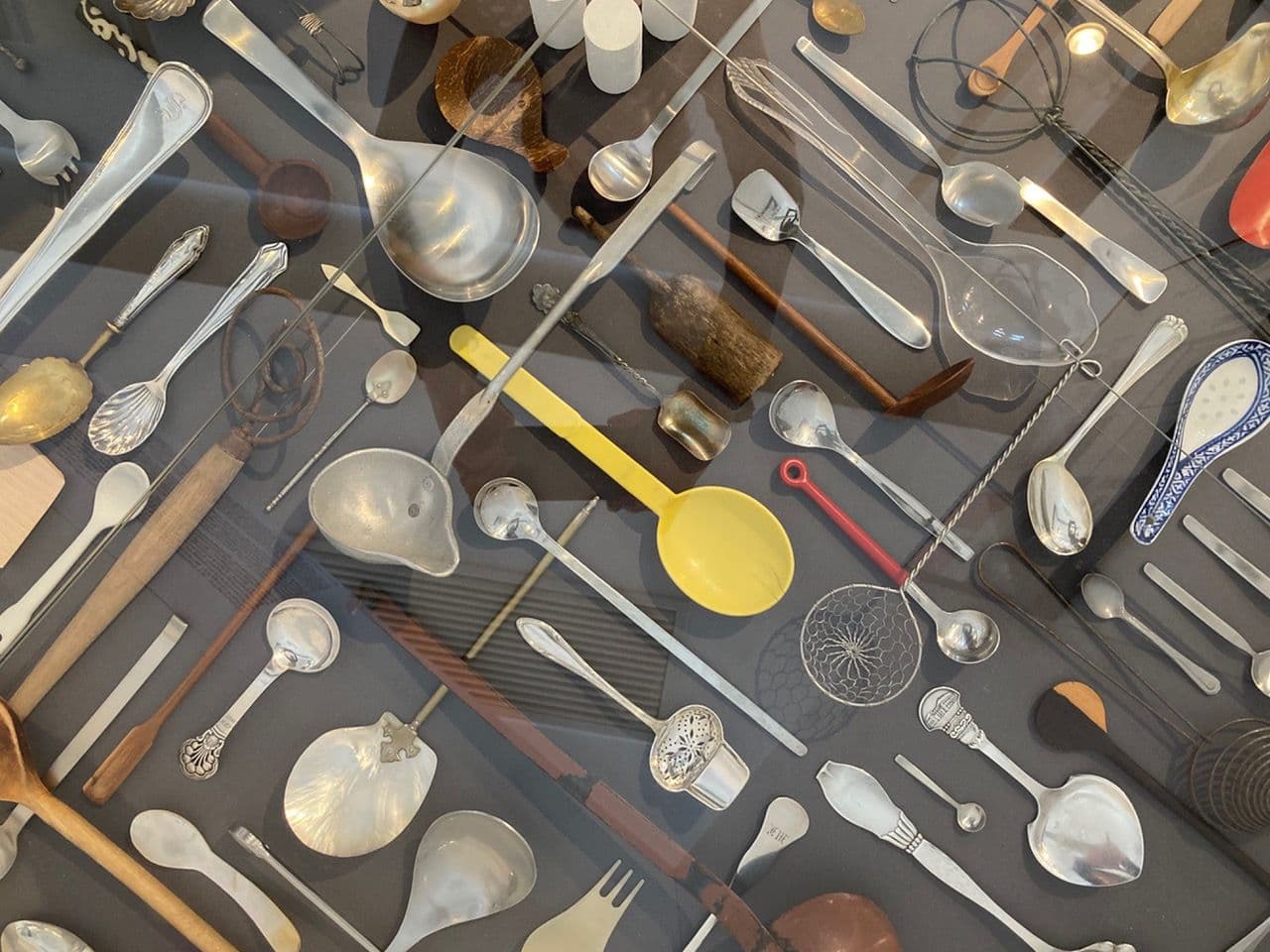 Verscheidene Löffel liegen in einer Glasvitrine zur Ausstellung