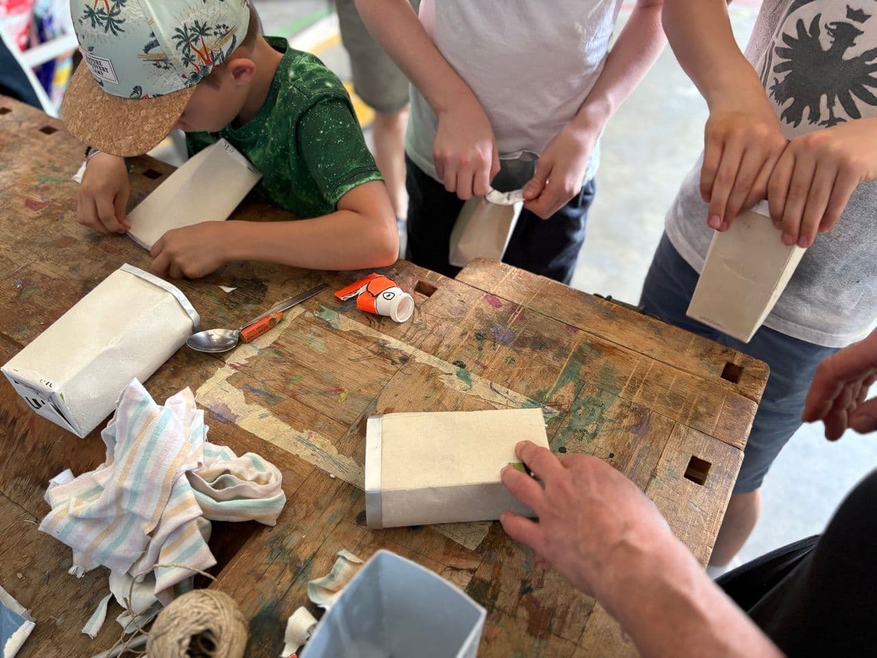 Hände, welche über einem Tisch arbeiten und werken