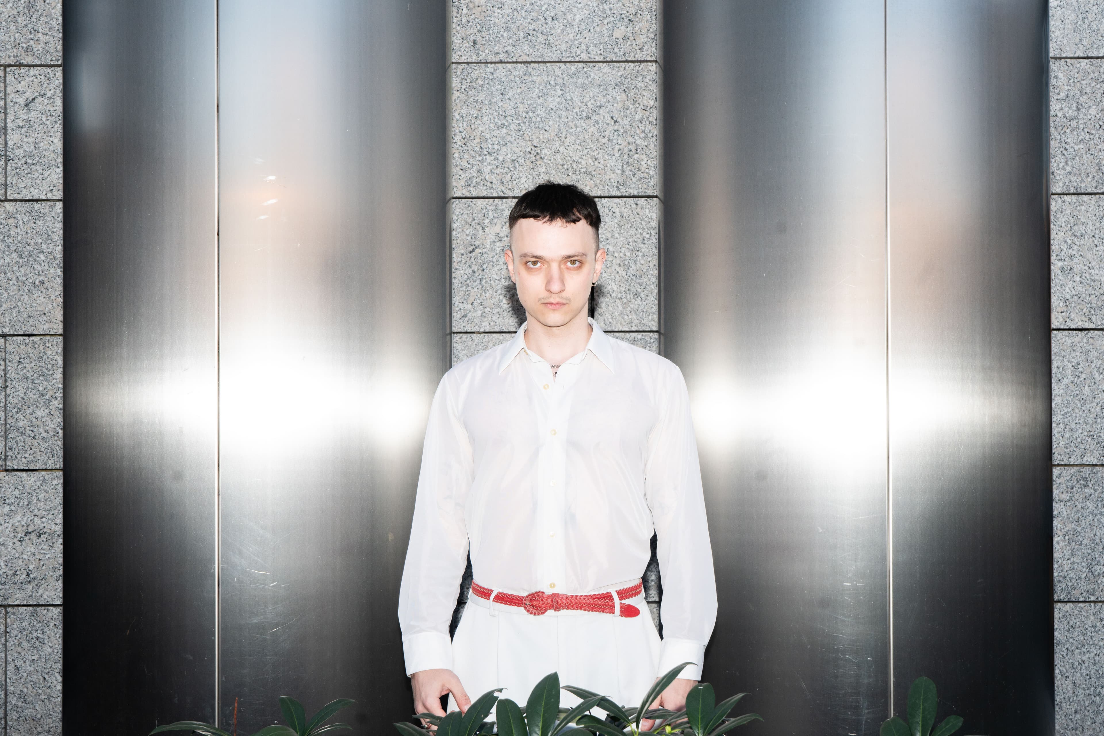 Eine Person steht zwischen zwei Metall-Elementen und schaut eindringlich in die Kamera.