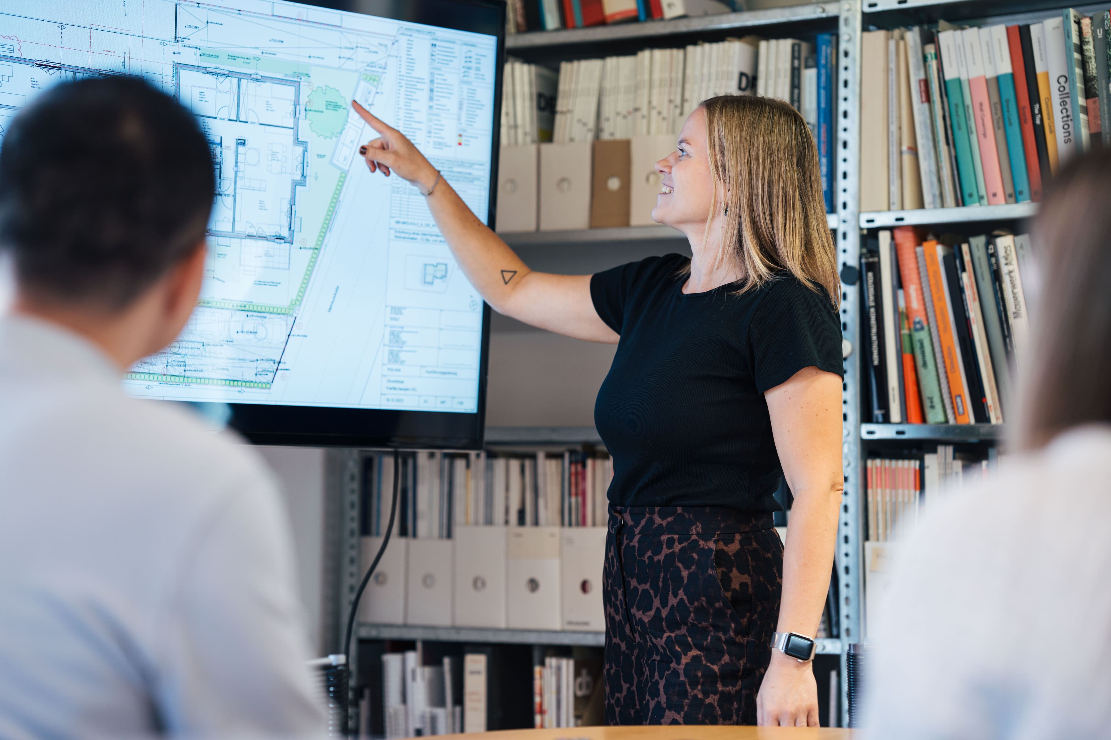 Eine Frau präsentiert einen architektonischen Plan auf einem Bildschirm