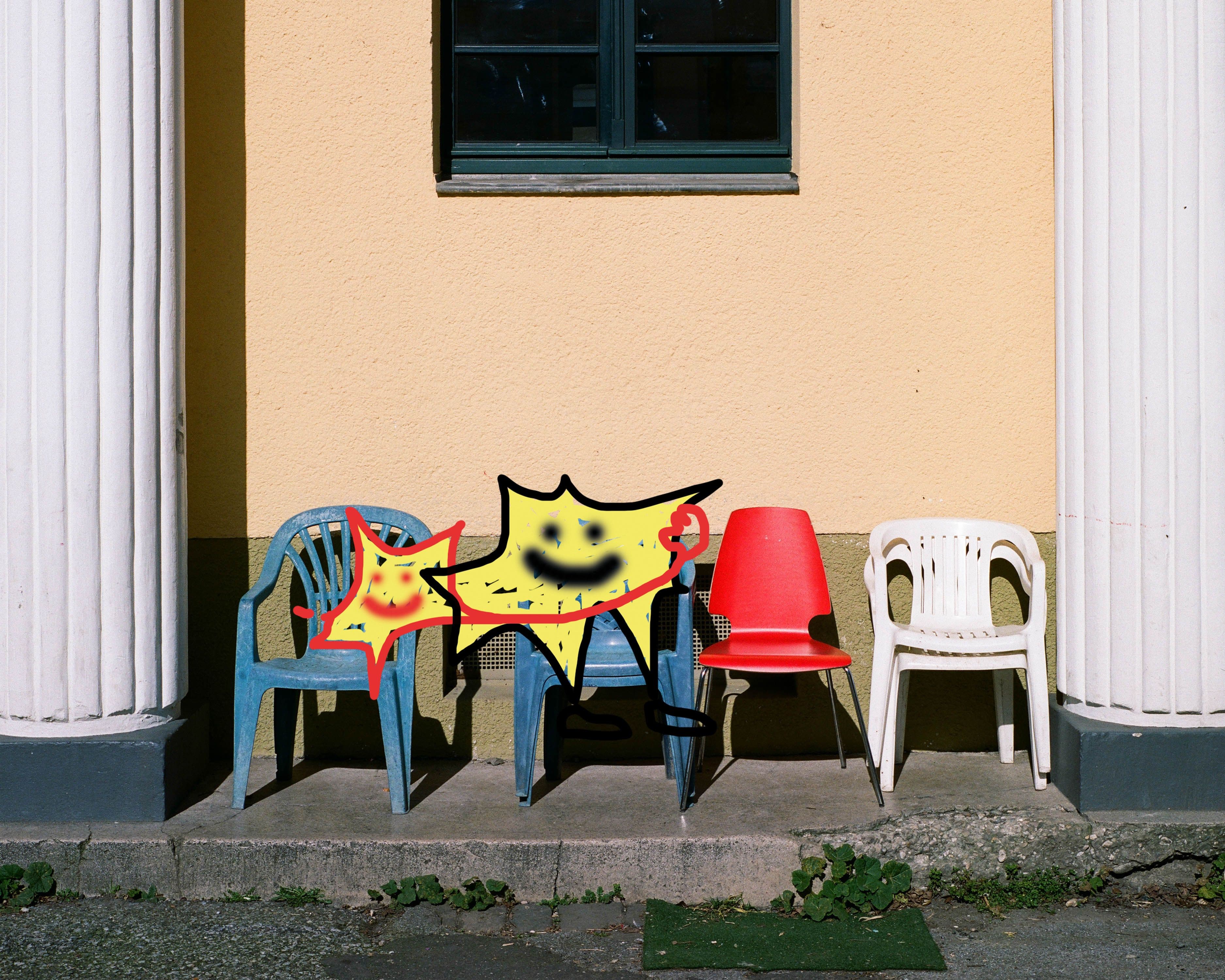 Stühle verschiedener Modelle und Farben stehen vor einer Hauswand