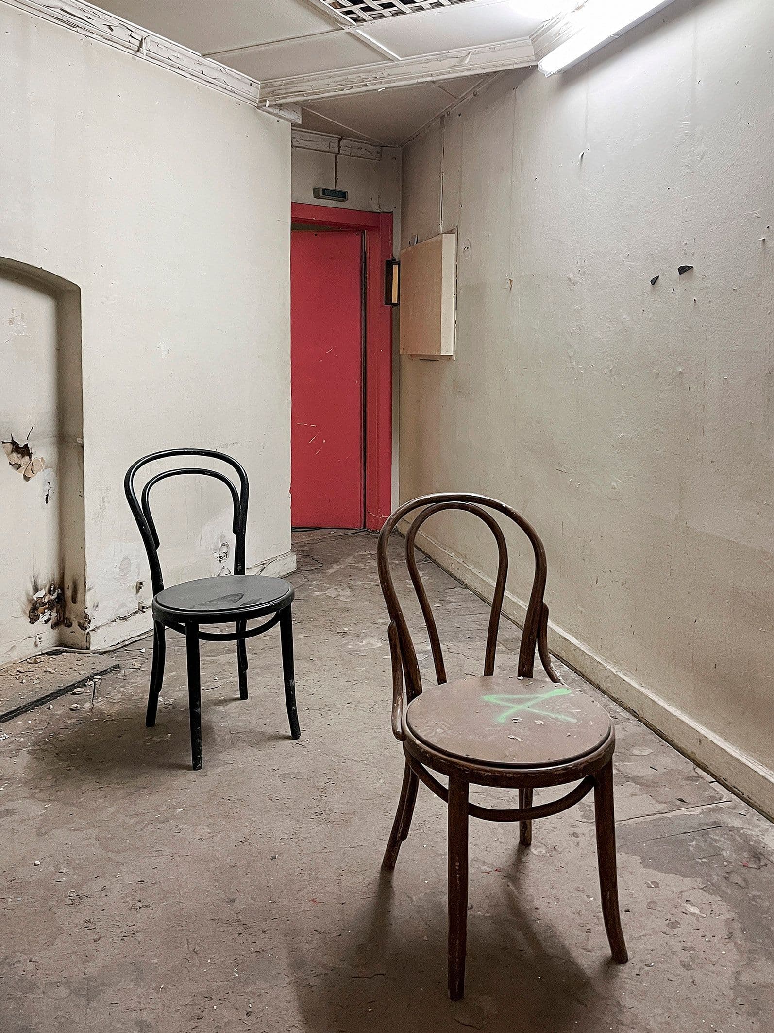 In einem etwas heruntergekommenen Raum stehen zwei Stühle.