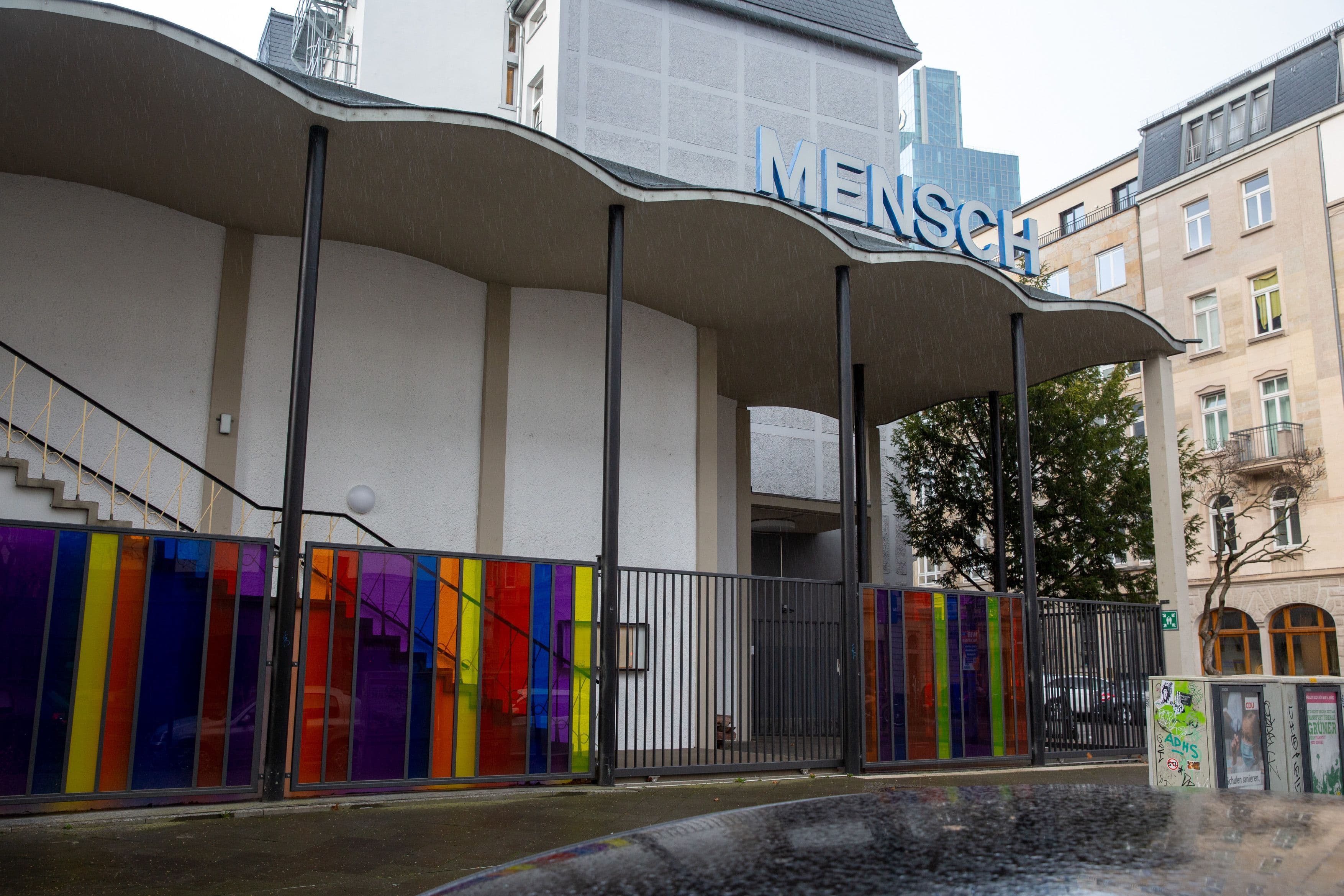 Zu sehen ist ein Gebäude mit bunten Verzierungen, auf dessen Dach der Schriftzug „Mensch” steht.