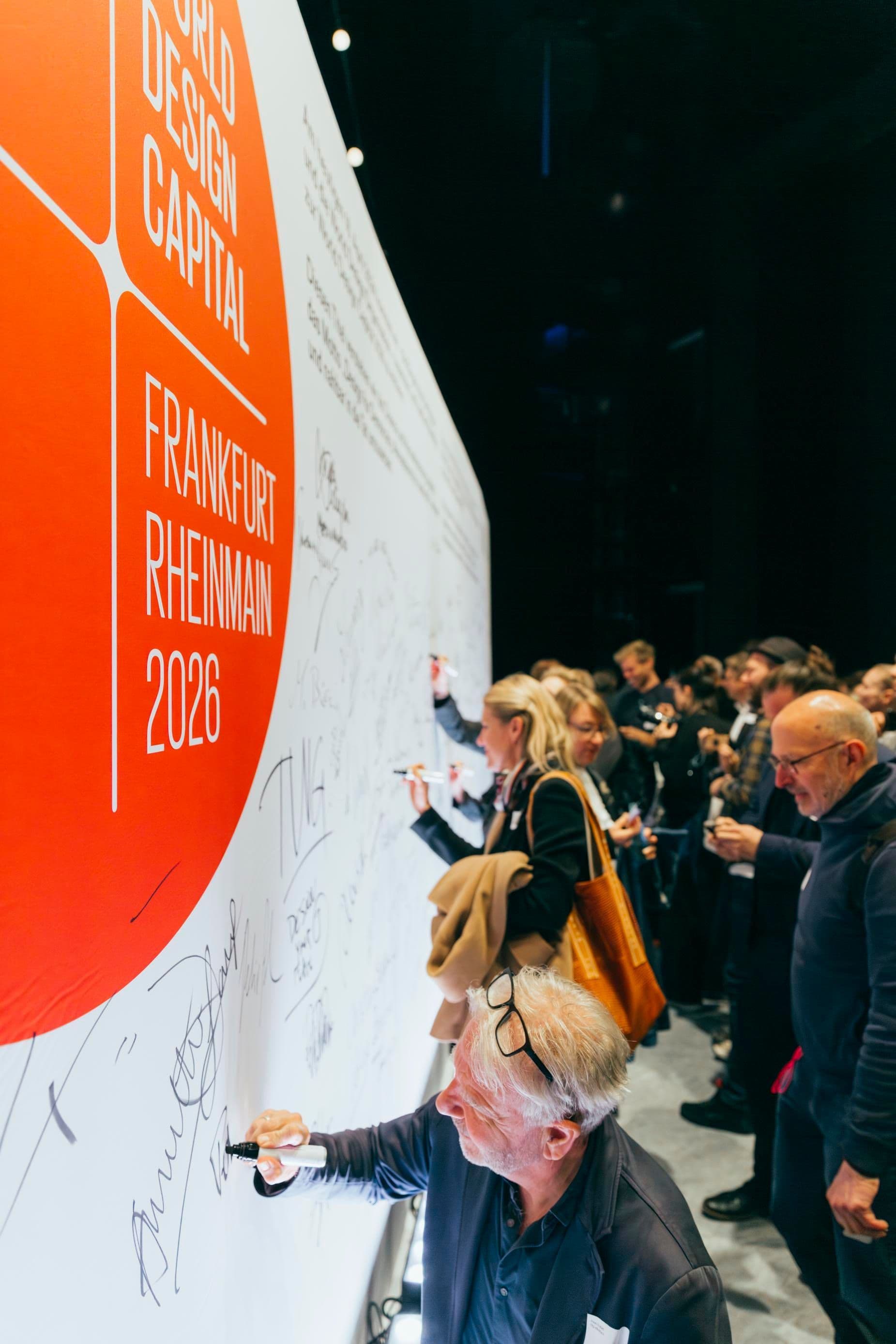 Viele Personen unterschreiben auf einer großen Tafel auf der Signing Ceremony von WDC 2026.