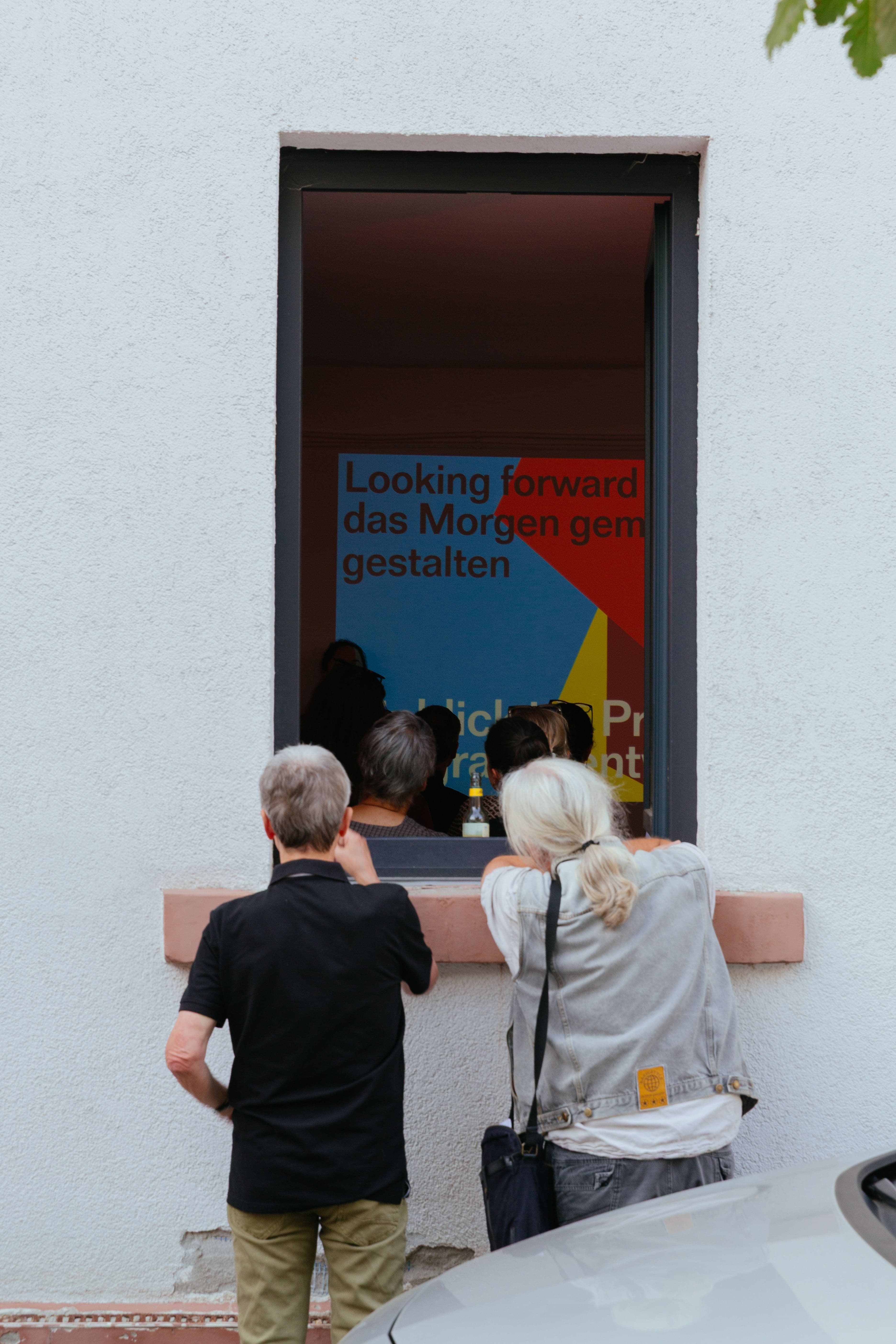 Zwei Personen schauen in ein offenes Fenster hinein.