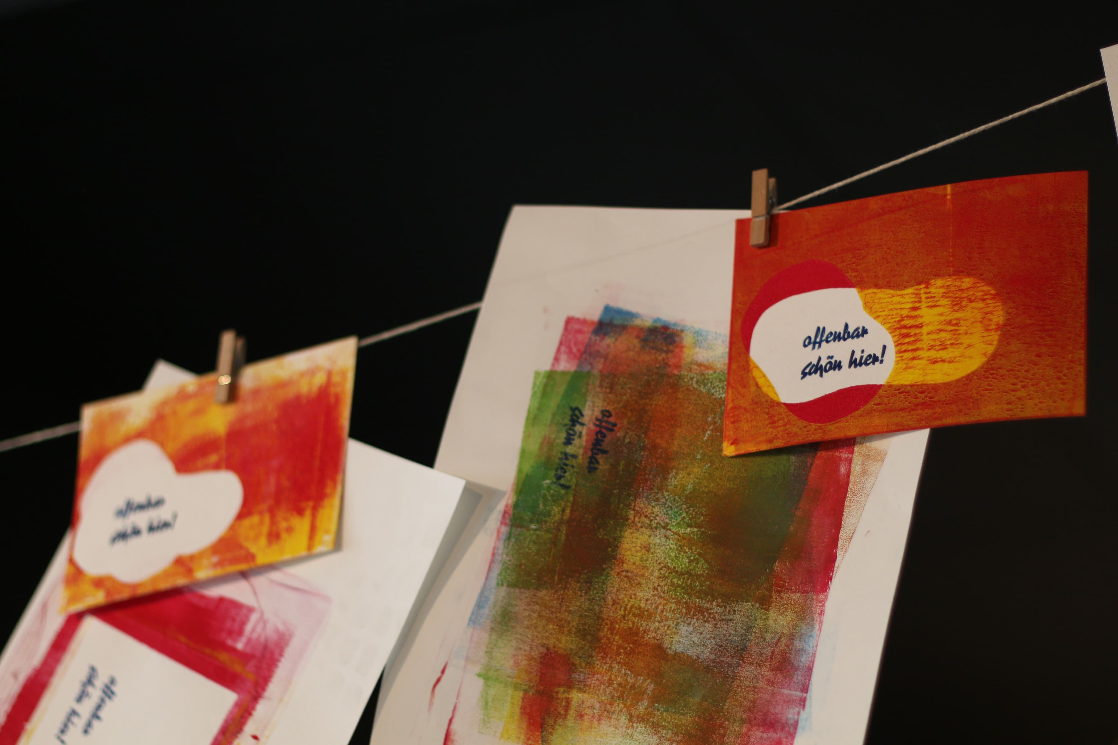 An einem Seil hängen verschiedene bedruckte Postkarten und Blätter.