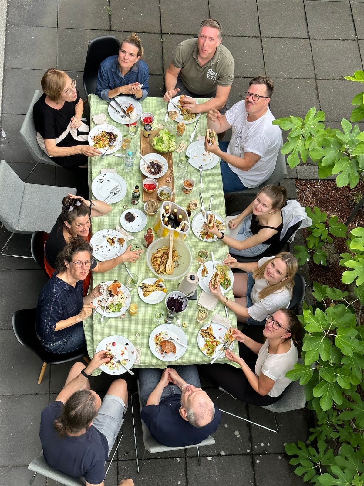 Menschen sitzen gemeinsam an einem großen gedeckten Tisch