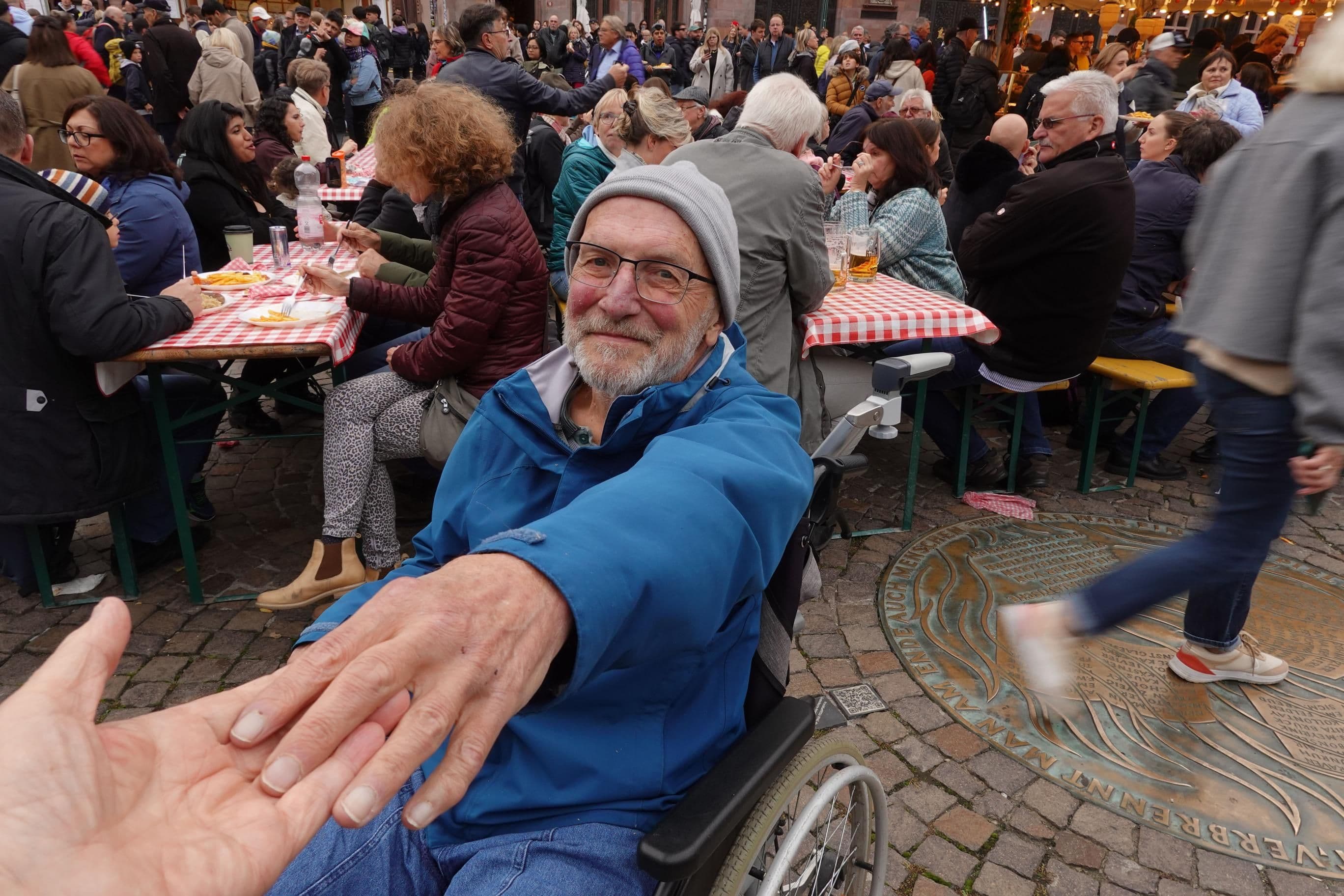 Eine Person reicht einer anderen Person im Rollstuhl die Hand.