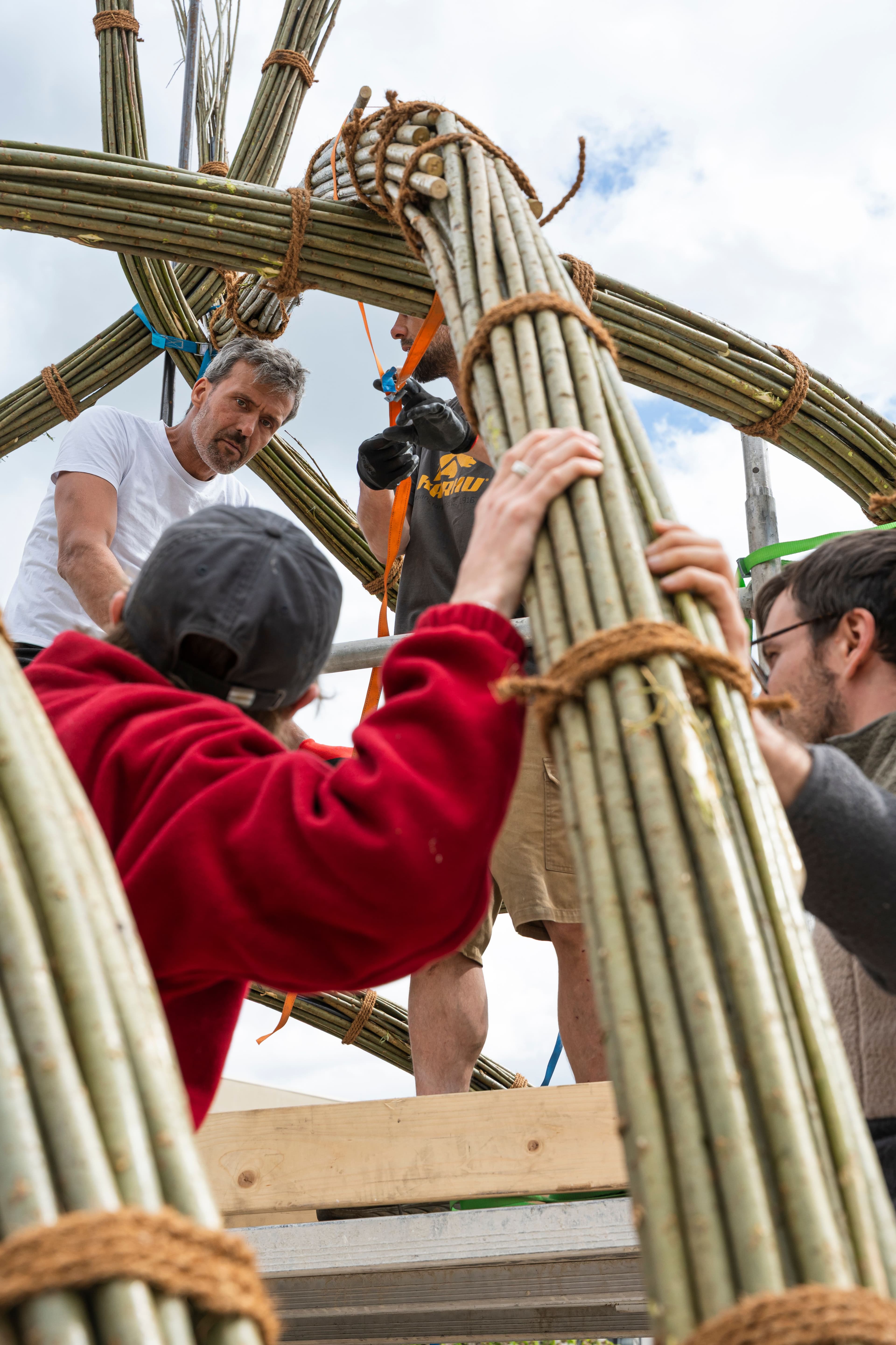 Menschen arbeiten mit Weidenstämmen und bauen einen Pavillon.