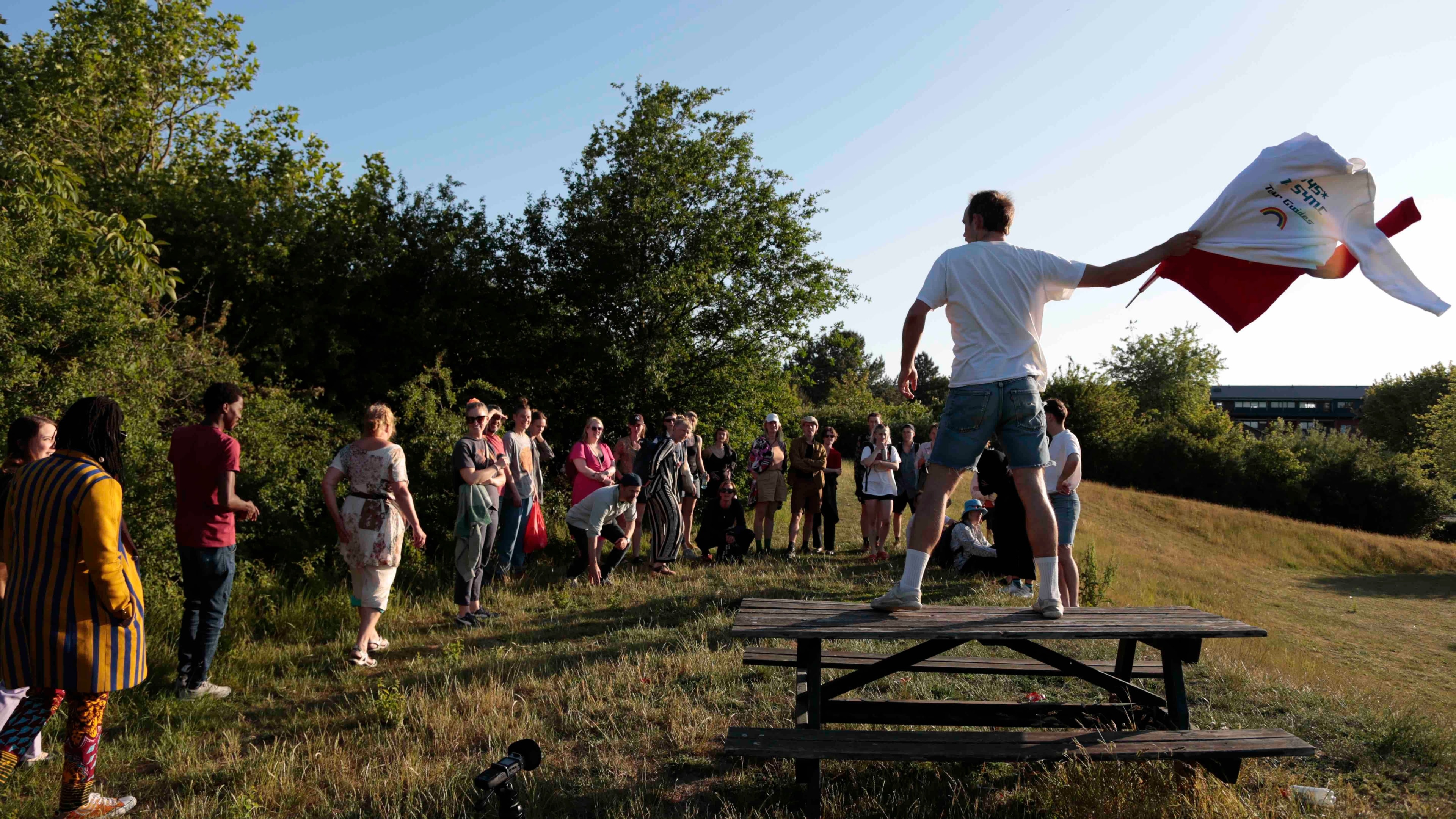 Eine Gruppe Personen, die zu einer Person auf einem Tisch aufschauen