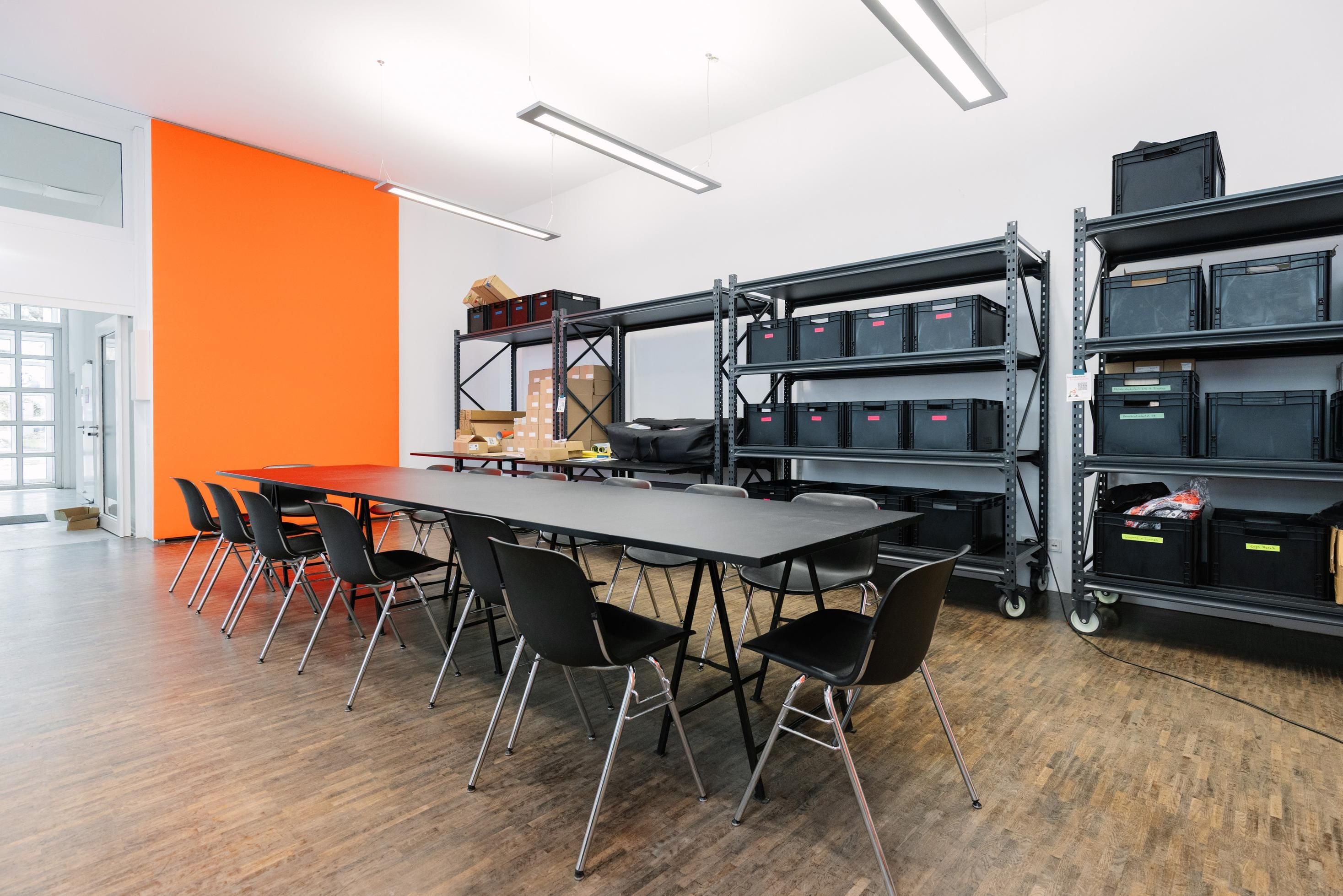 Ein Raum mit einem großen Tisch und vielen schwarzen Regalen.