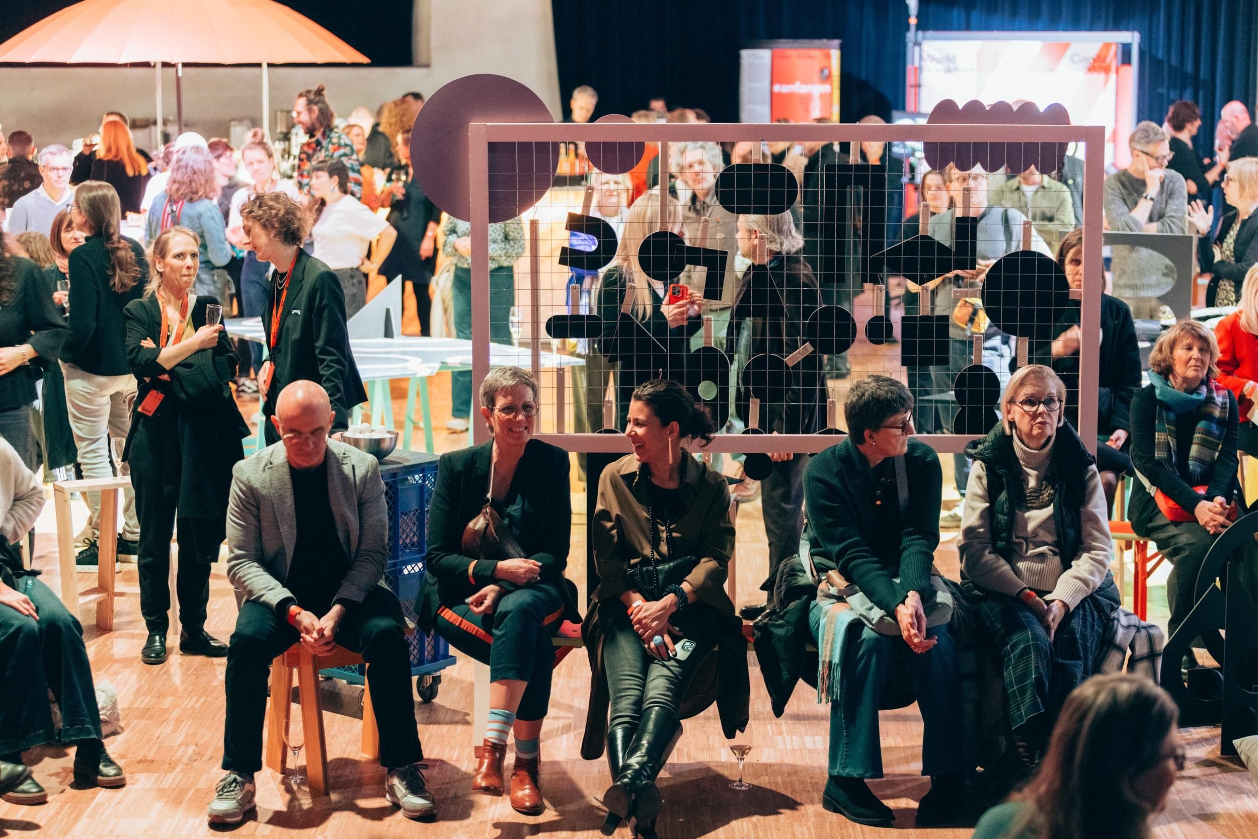 Viele Menschen sitzen und stehen in einem Raum zusammen.