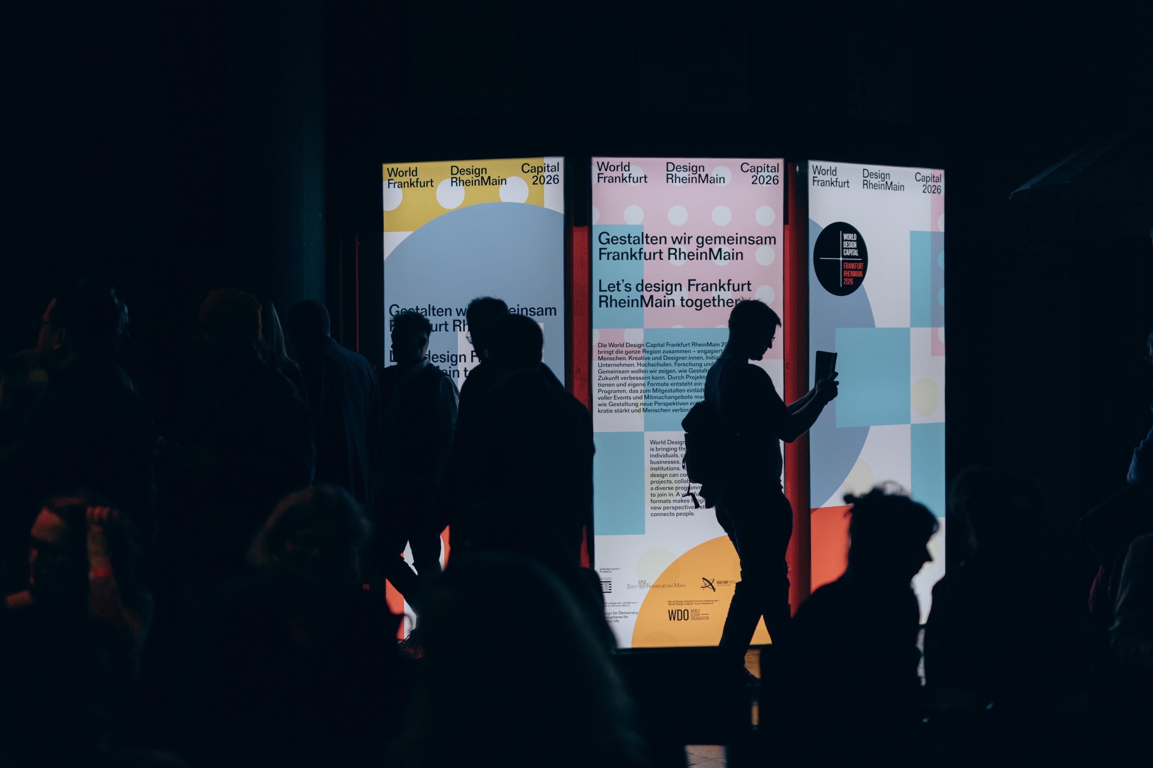 Menschen stehen vor Leuchtkästen der WDC2026