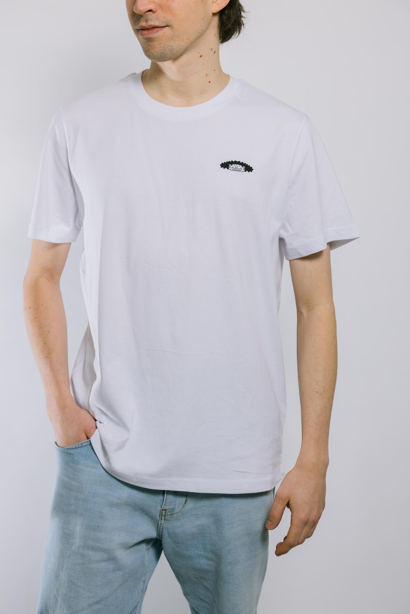 Eine Person trägt ein weißes Shirt mit einer kleinen schwarzen Illustration, die einen Wuschelkopf zeigt.