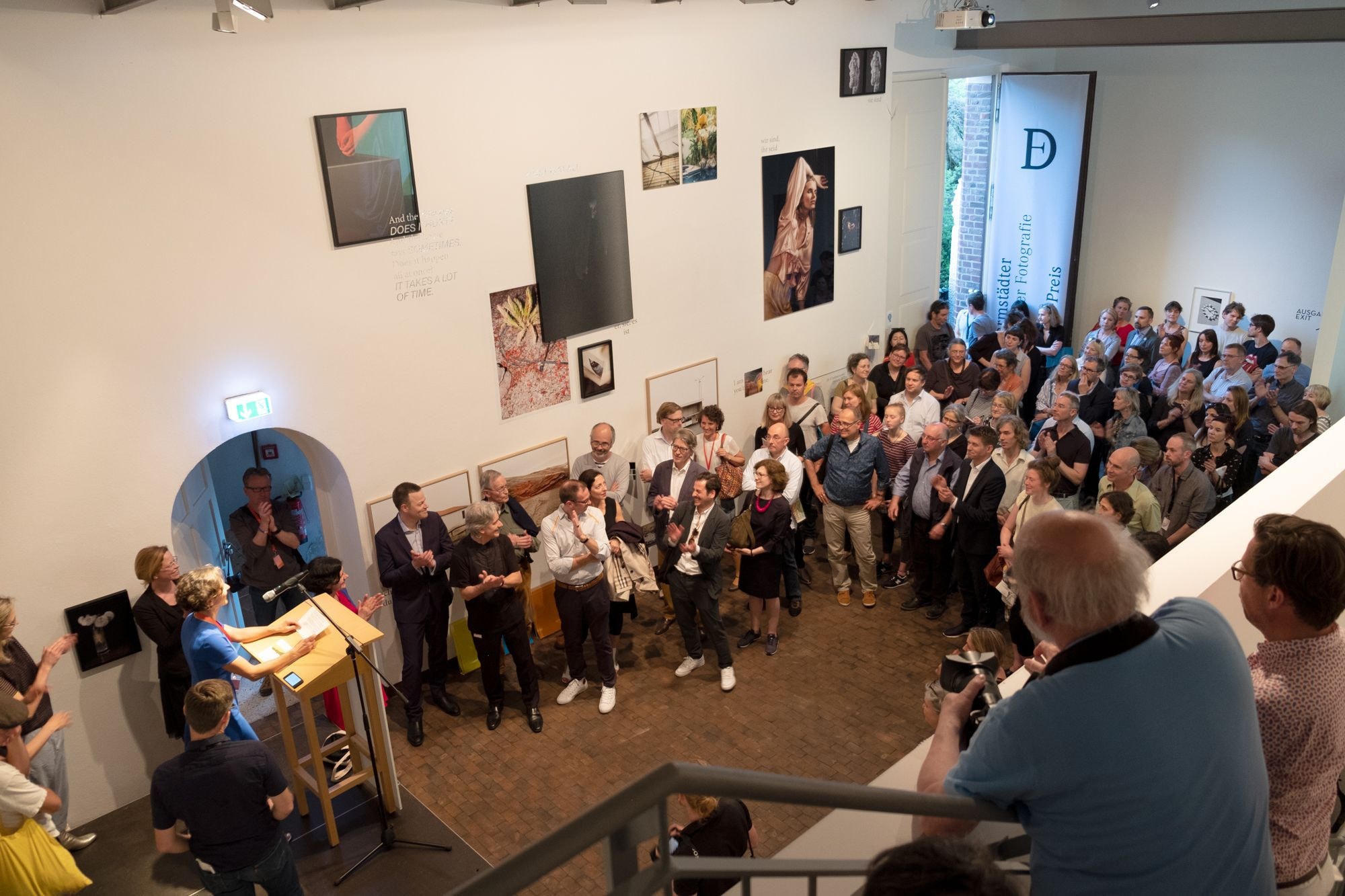 Menschen schauen der Preisverleihung der Darmstädter Tage der Fotografie zu