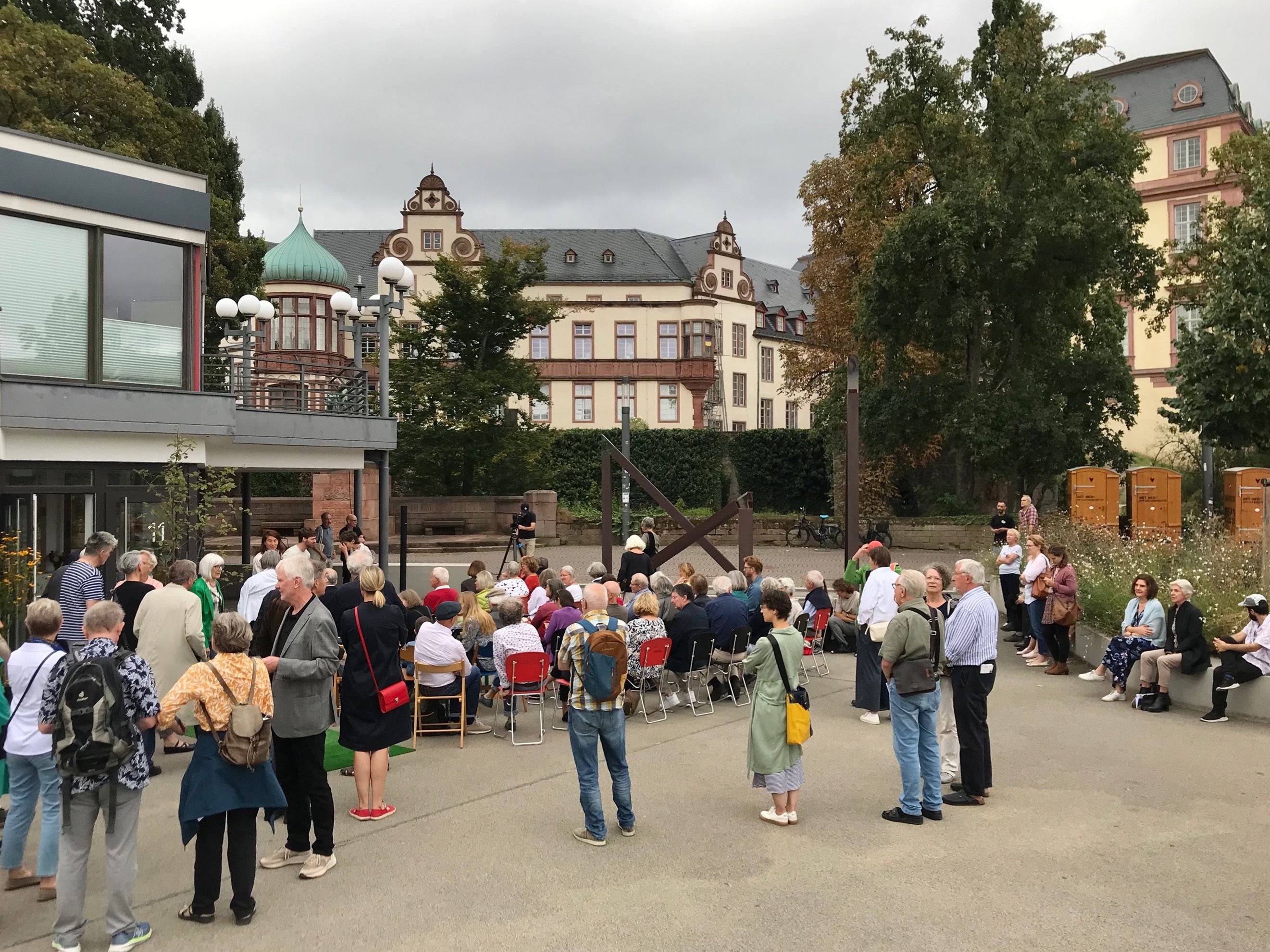 Menschen stehen im Rahmen einer Vernissage auf einem Platz in Darmstadt