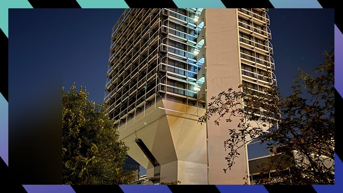Ein Hochhaus mit vielen Fenstern vor dunklem Himmel.