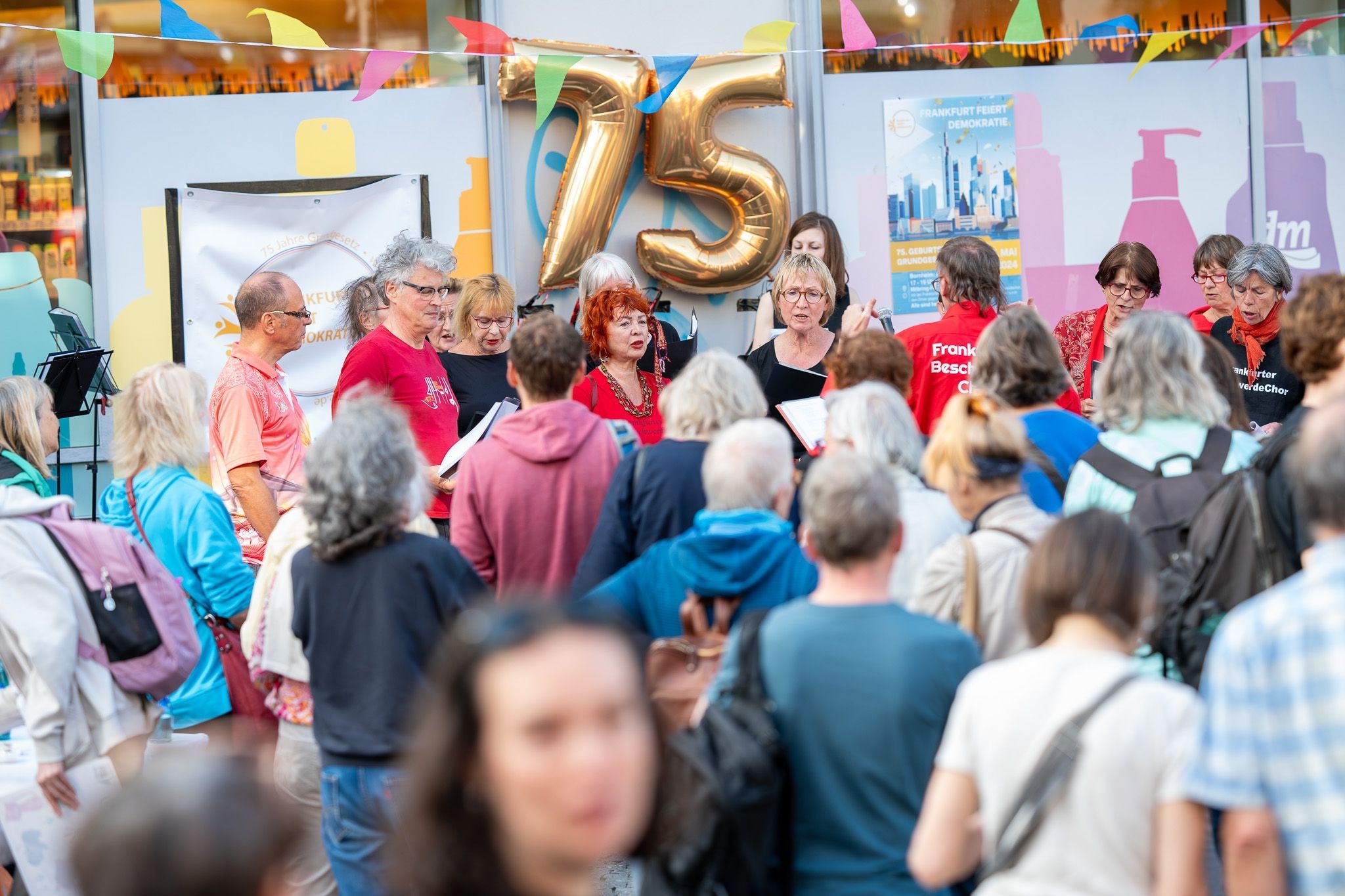 Eine Menschenmenge schaut einer Gruppe von Leuten zu, die vor einem Geschäft singt.