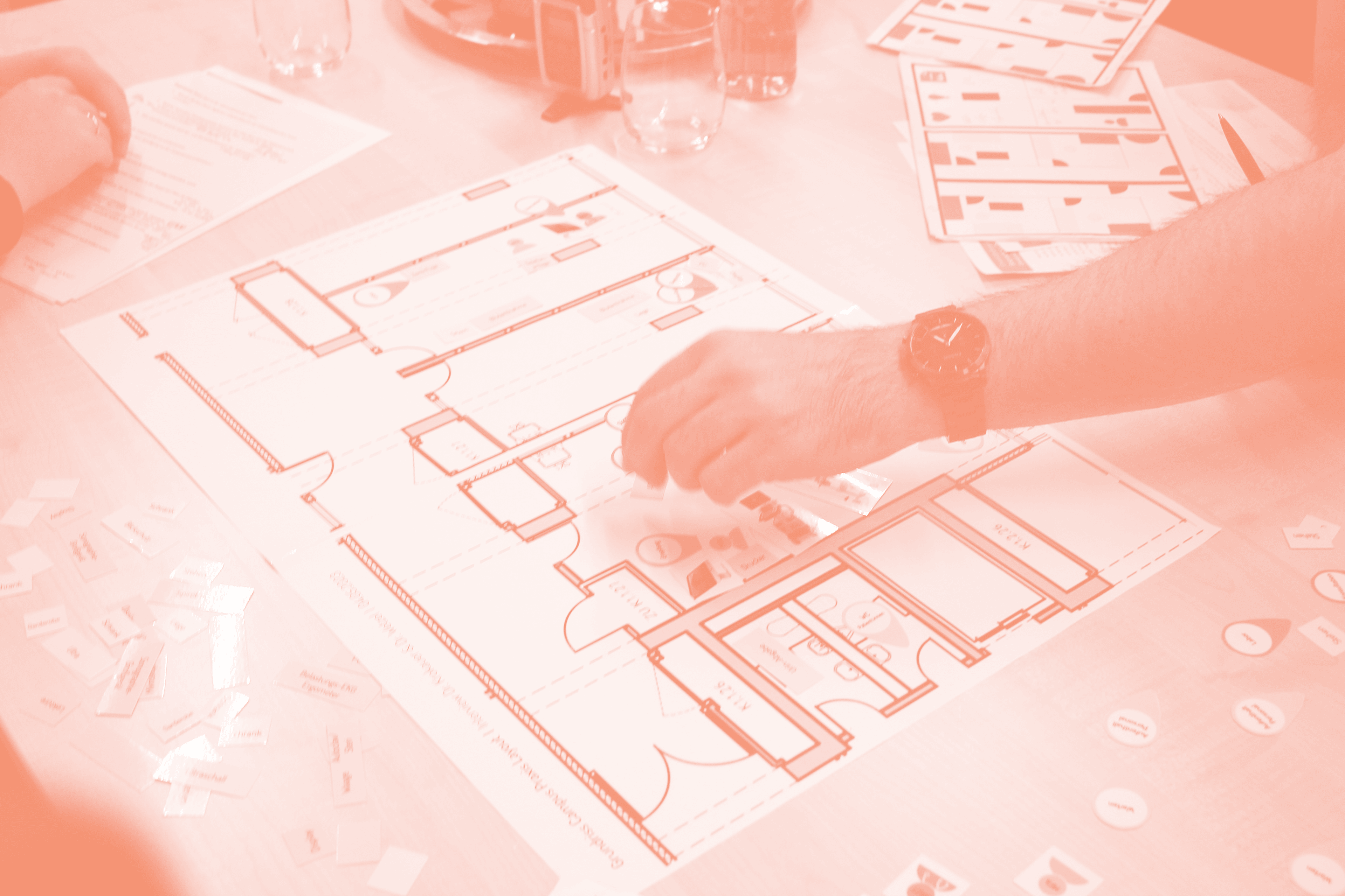 Eine Hand legt einen Gegenstand auf einen ausgedruckten Grundriss