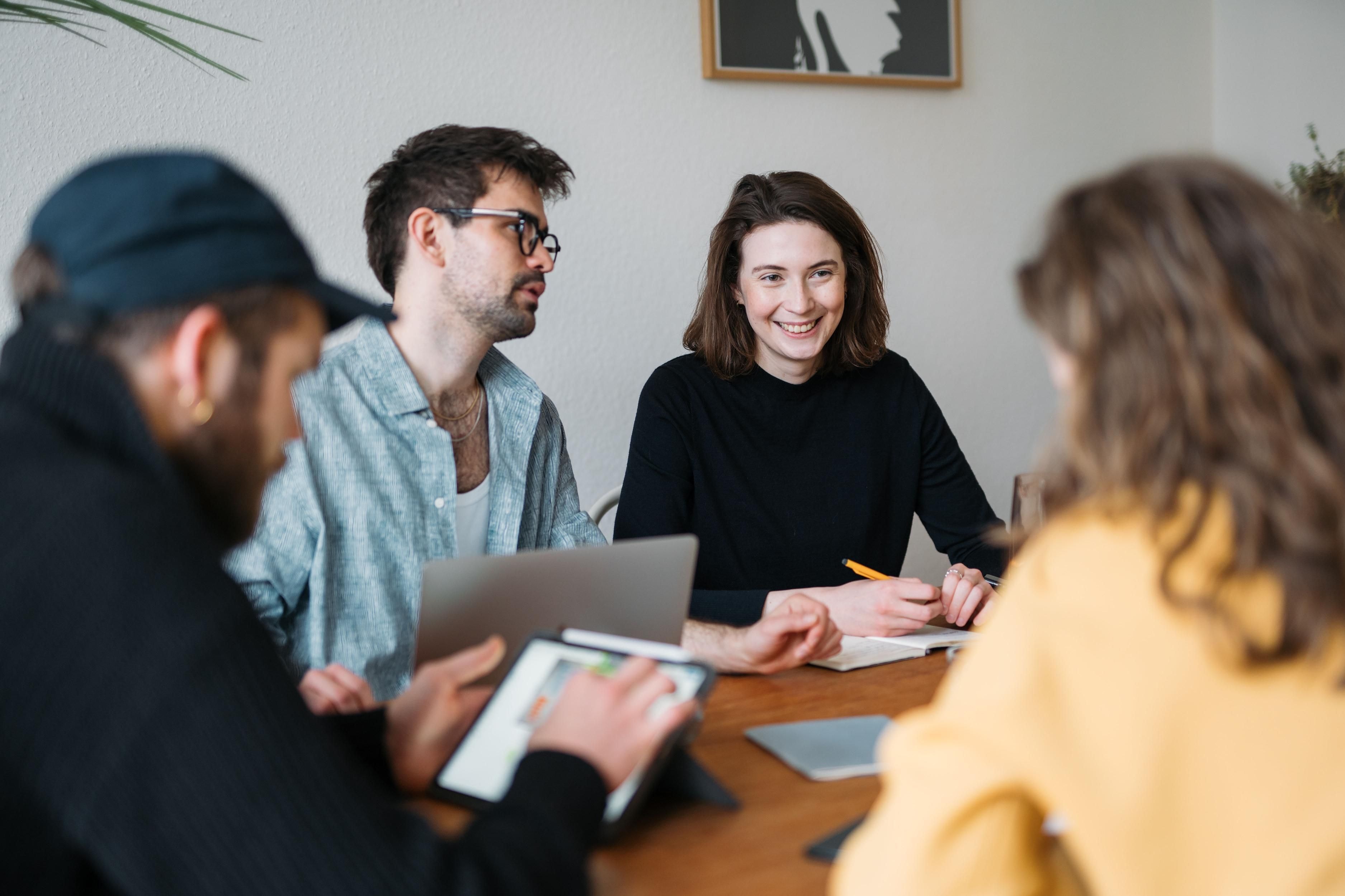 Mehrere Personen sitzen an einem Tisch und sind in einem Meeting.
